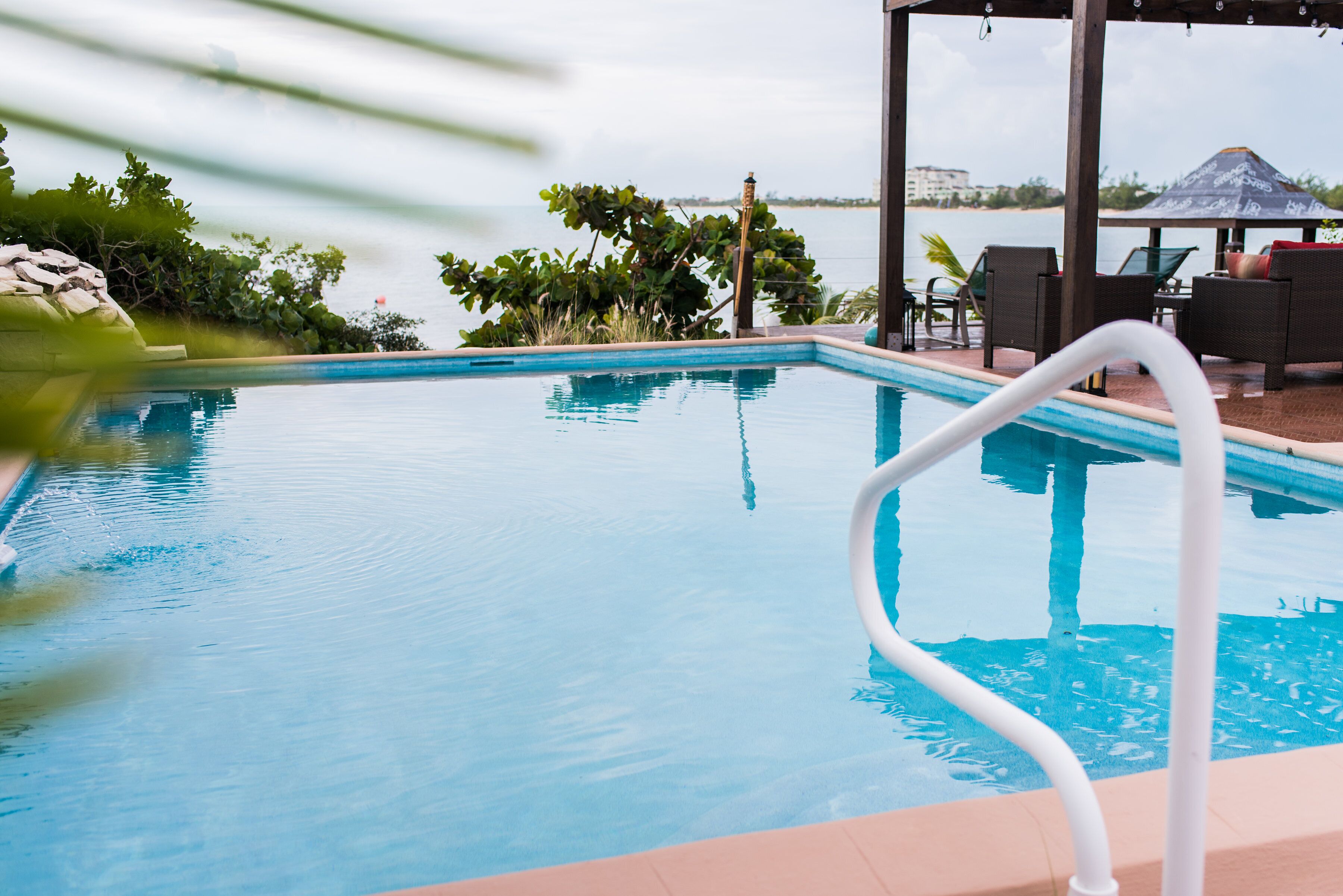 The pool with a view of the sea and a covered seating area.