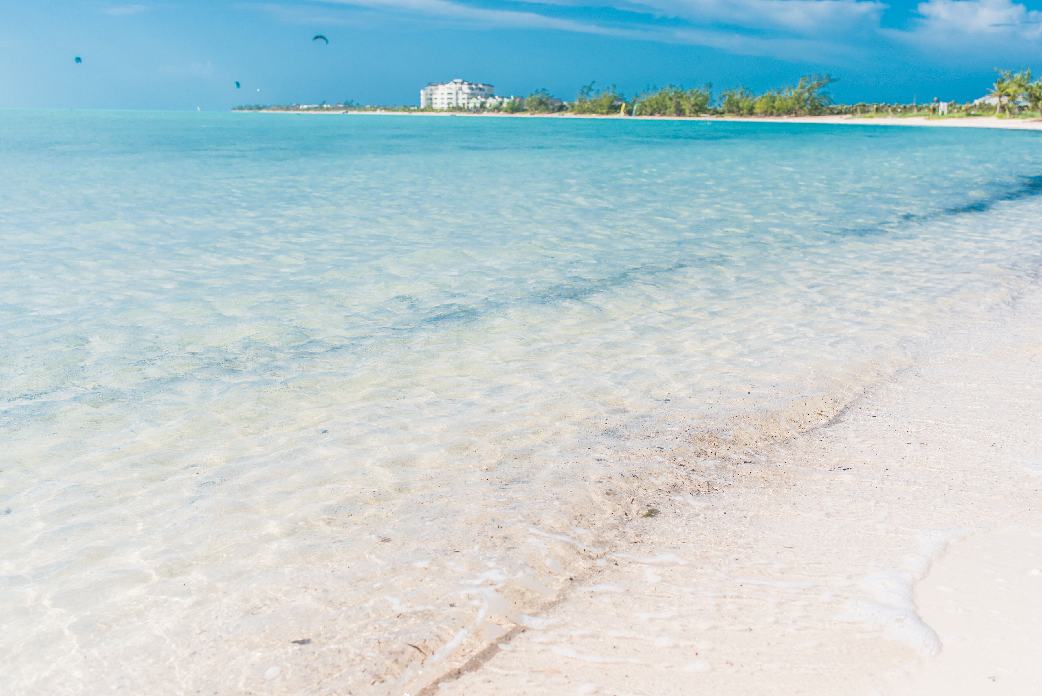 Clear shallow water at the beach with buildings far away.