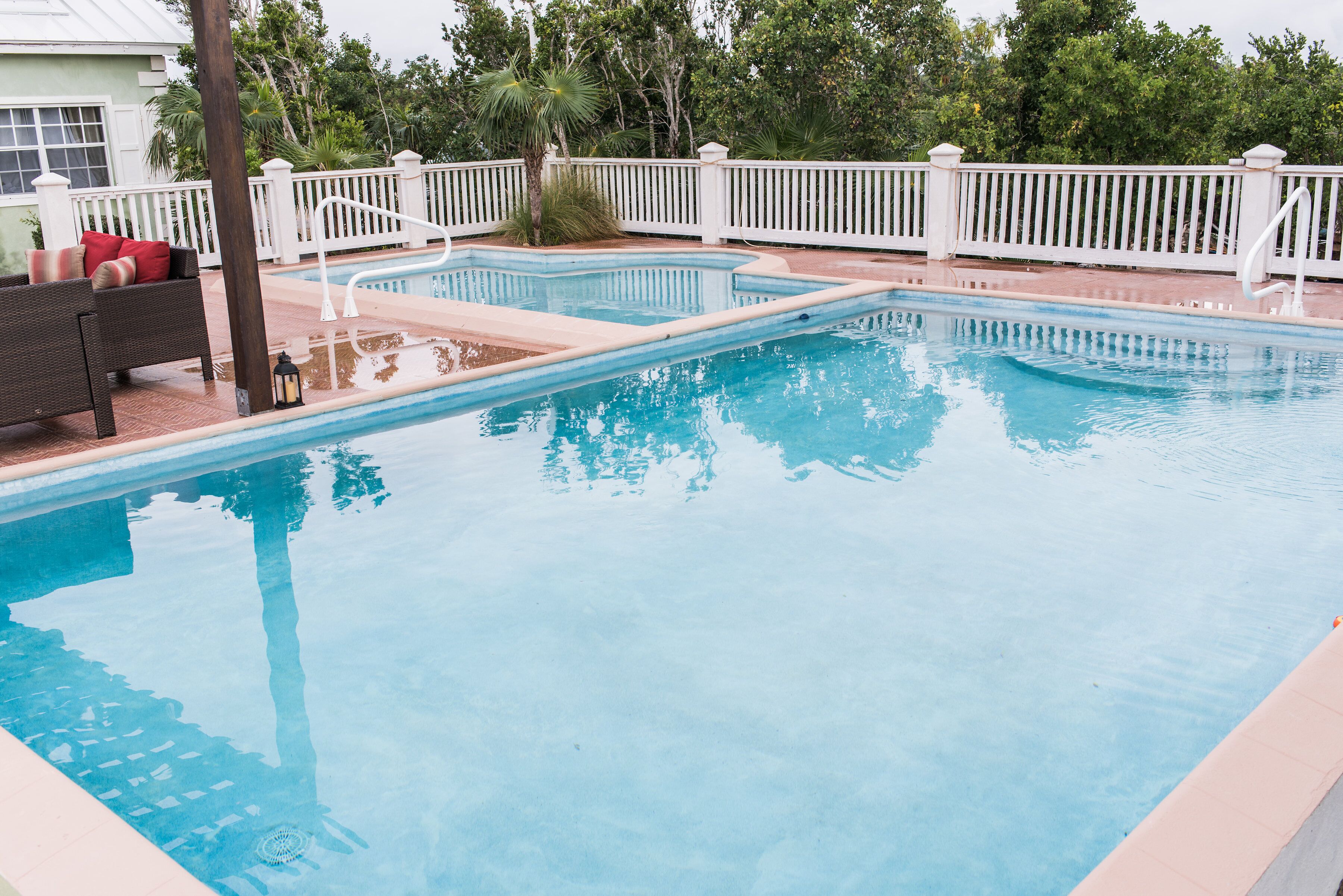 The pool with a white fence and trees around it.