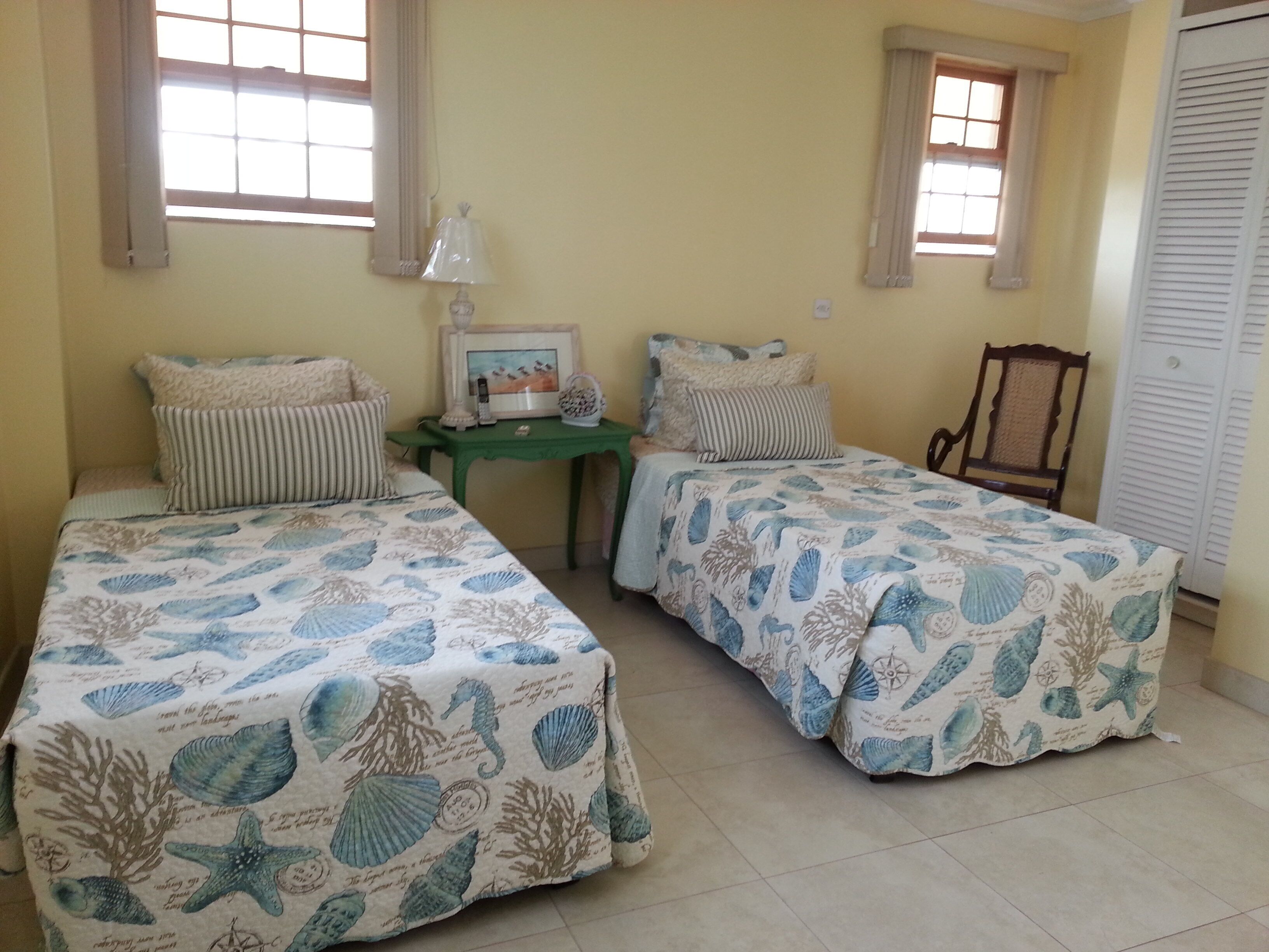 A bedroom with two single beds and a green side table.