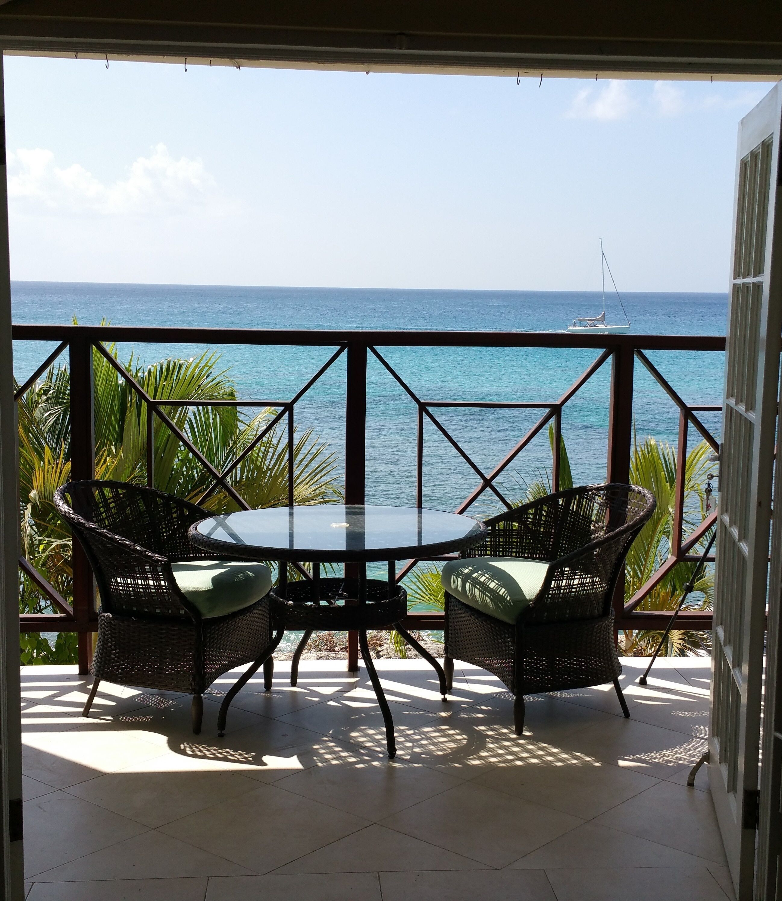 A table and two chairs on the balcony, with a view of the sea.