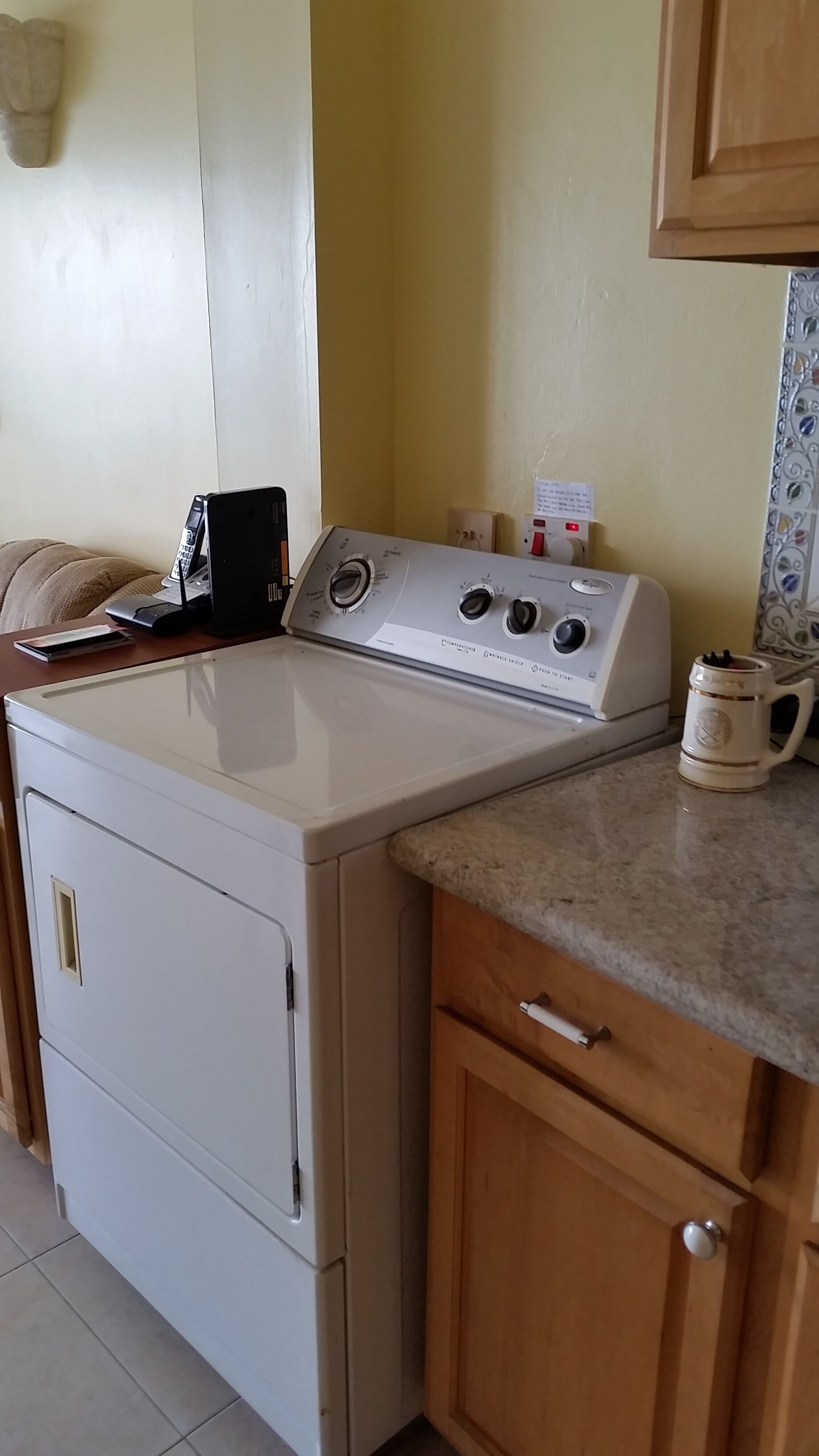 The laundry dryer beside the kitchen counter.