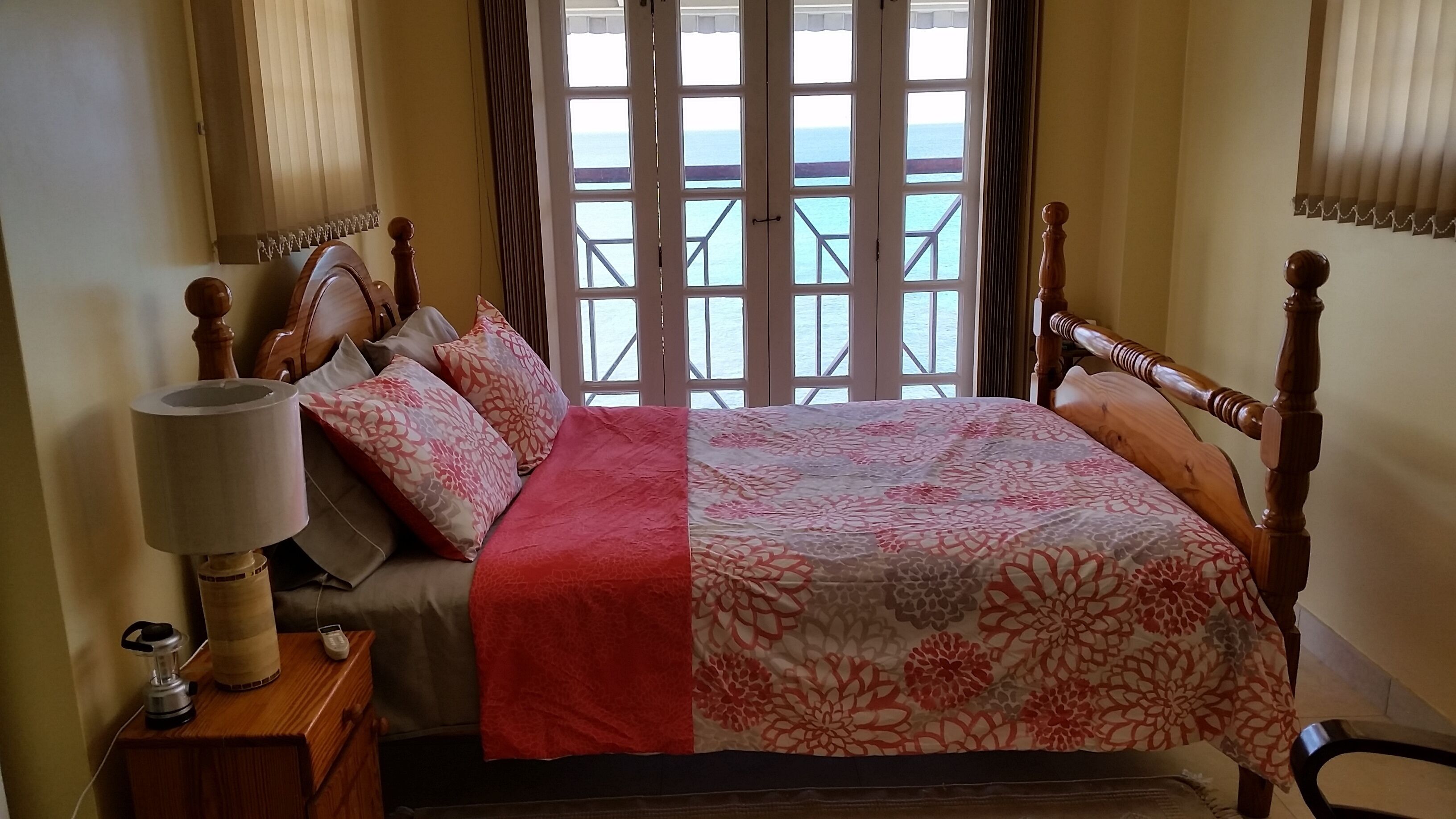 A bedroom with a double bed and glass doors, with a view of the sea.