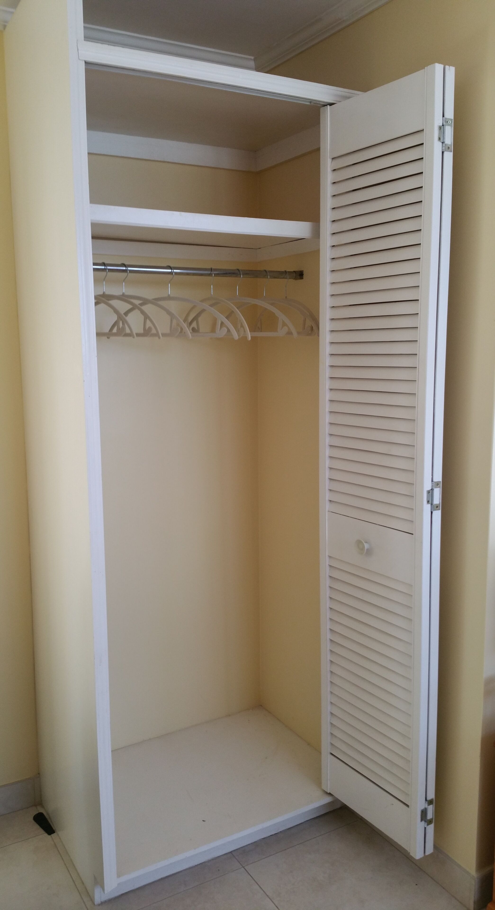 A closet with a shelf, a rail, and hangers.