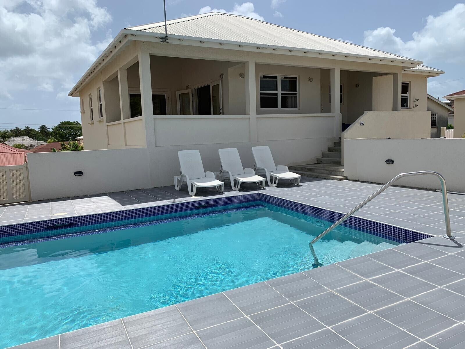 The pool and three lounge chairs in front of the villa.