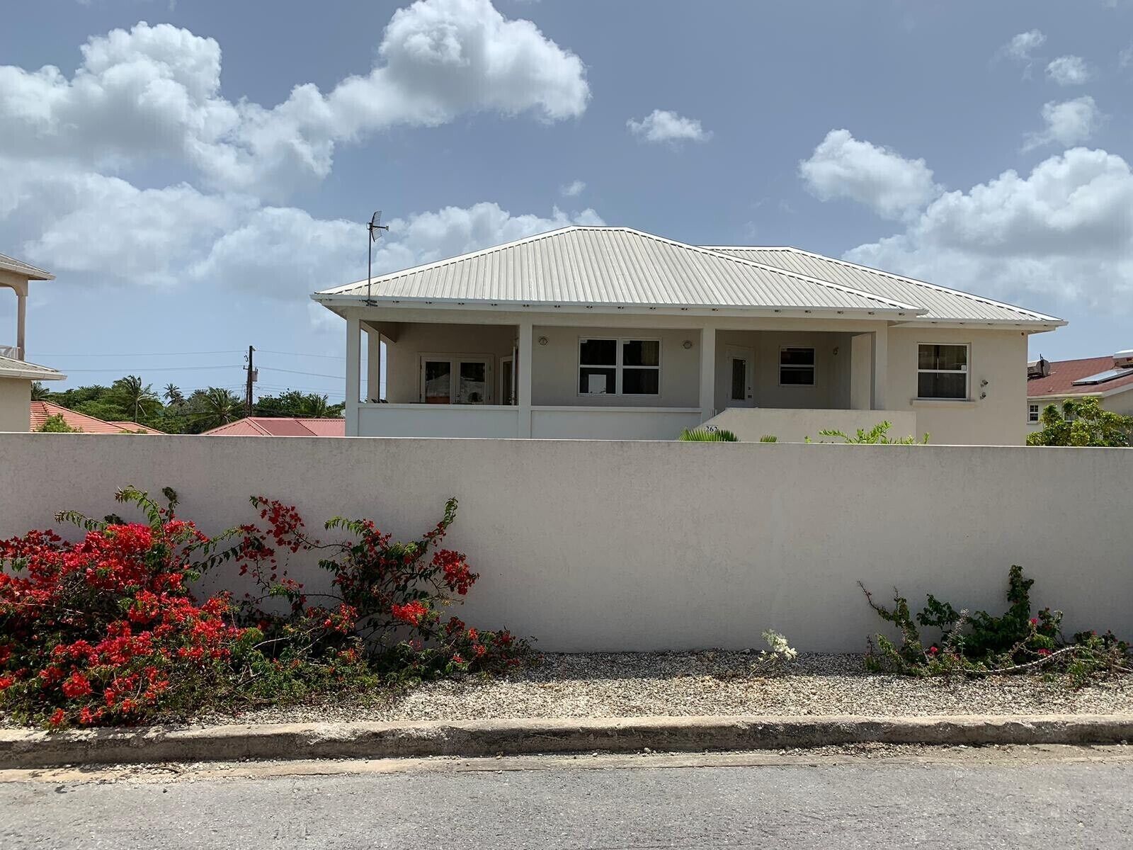 The villa behind a white wall with red flowers.