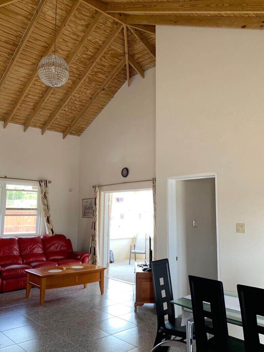 A living room with a red leather sofa and a wood ceiling.