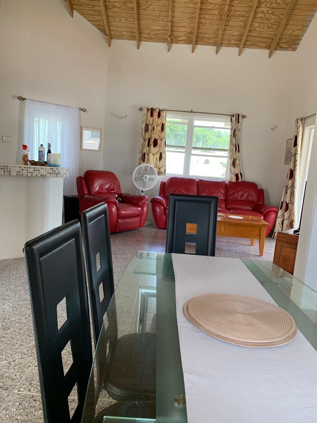 A view from the dining table to the living room with red leather sofas.