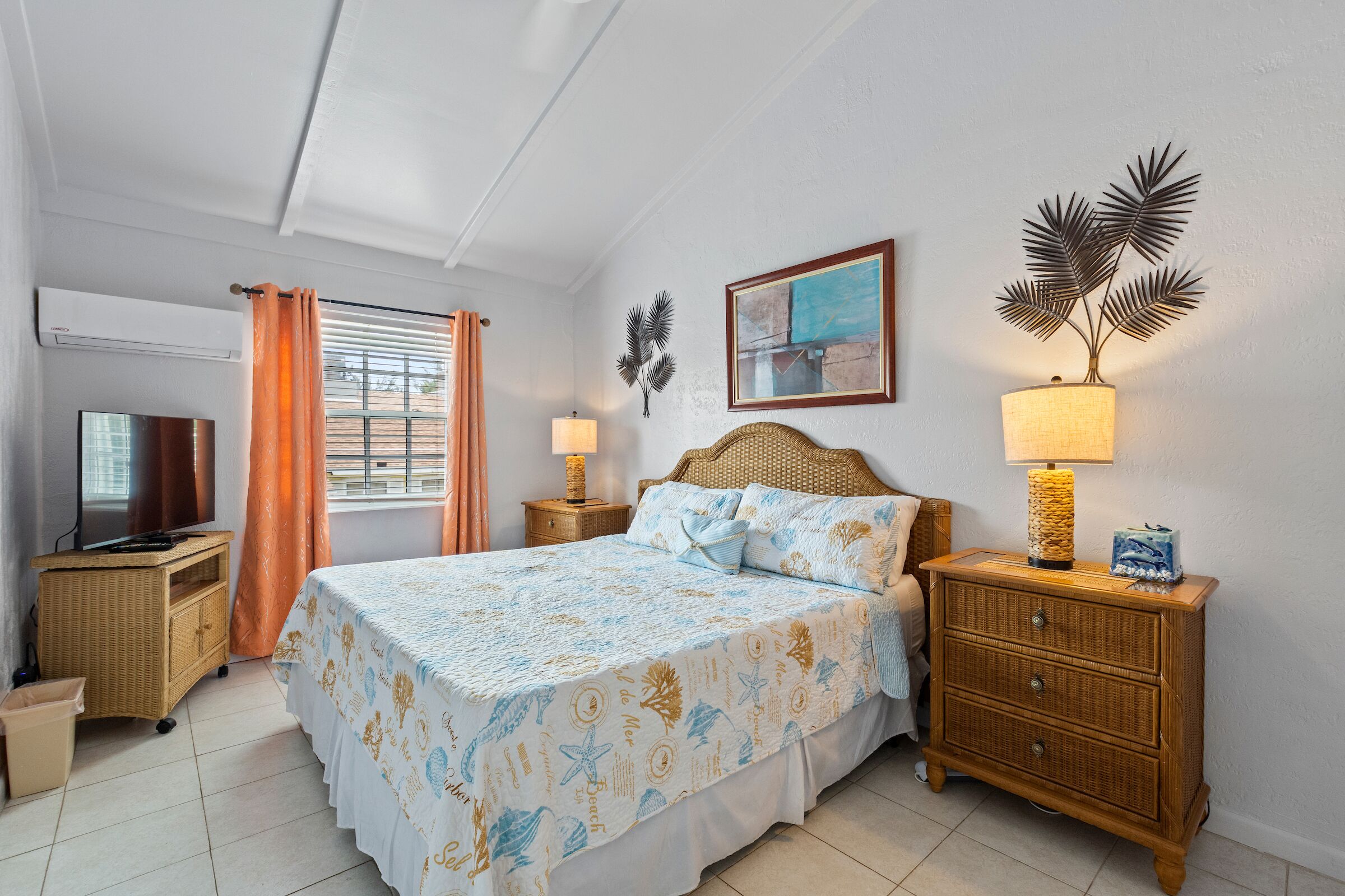 A bedroom with a wicker headboard and a television.