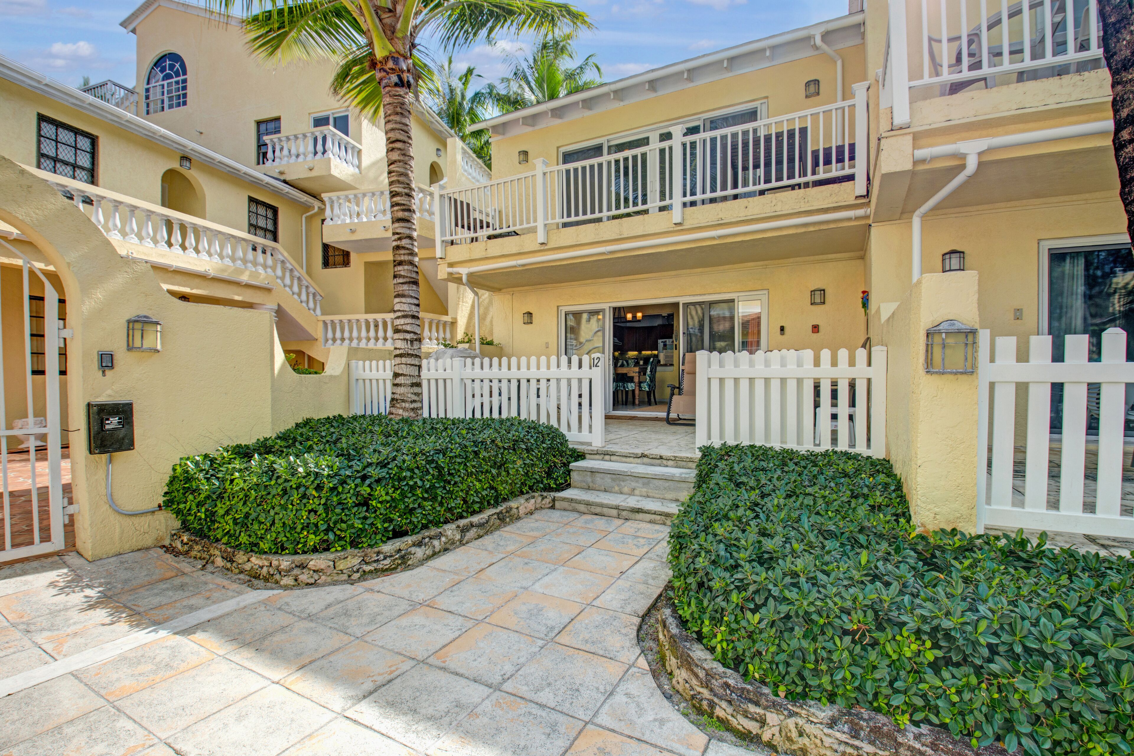 The front entrance of villa 12, with a white picket fence and a paved path.