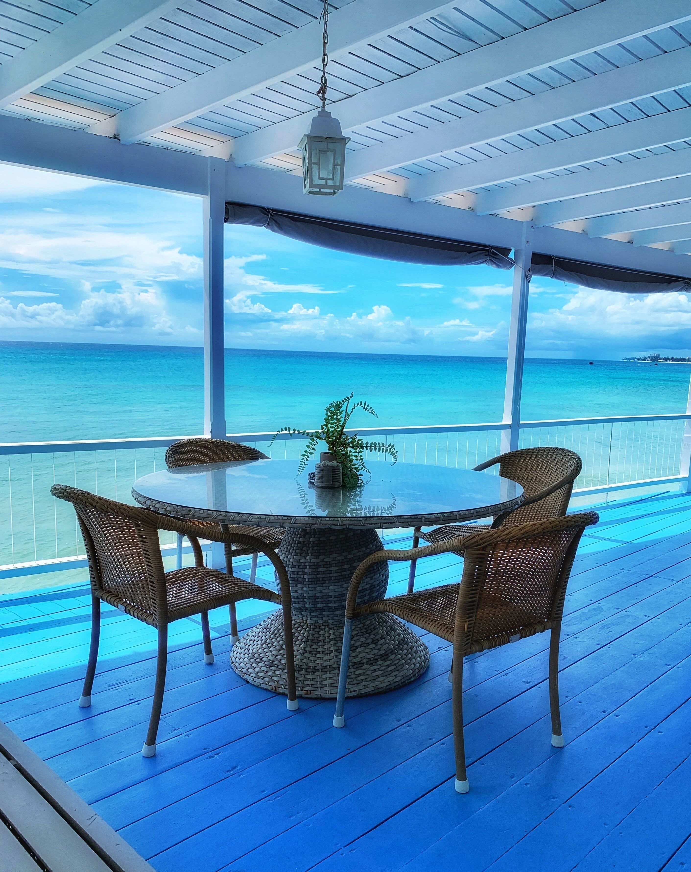 The covered deck with a round table and chairs, with a sea view.
