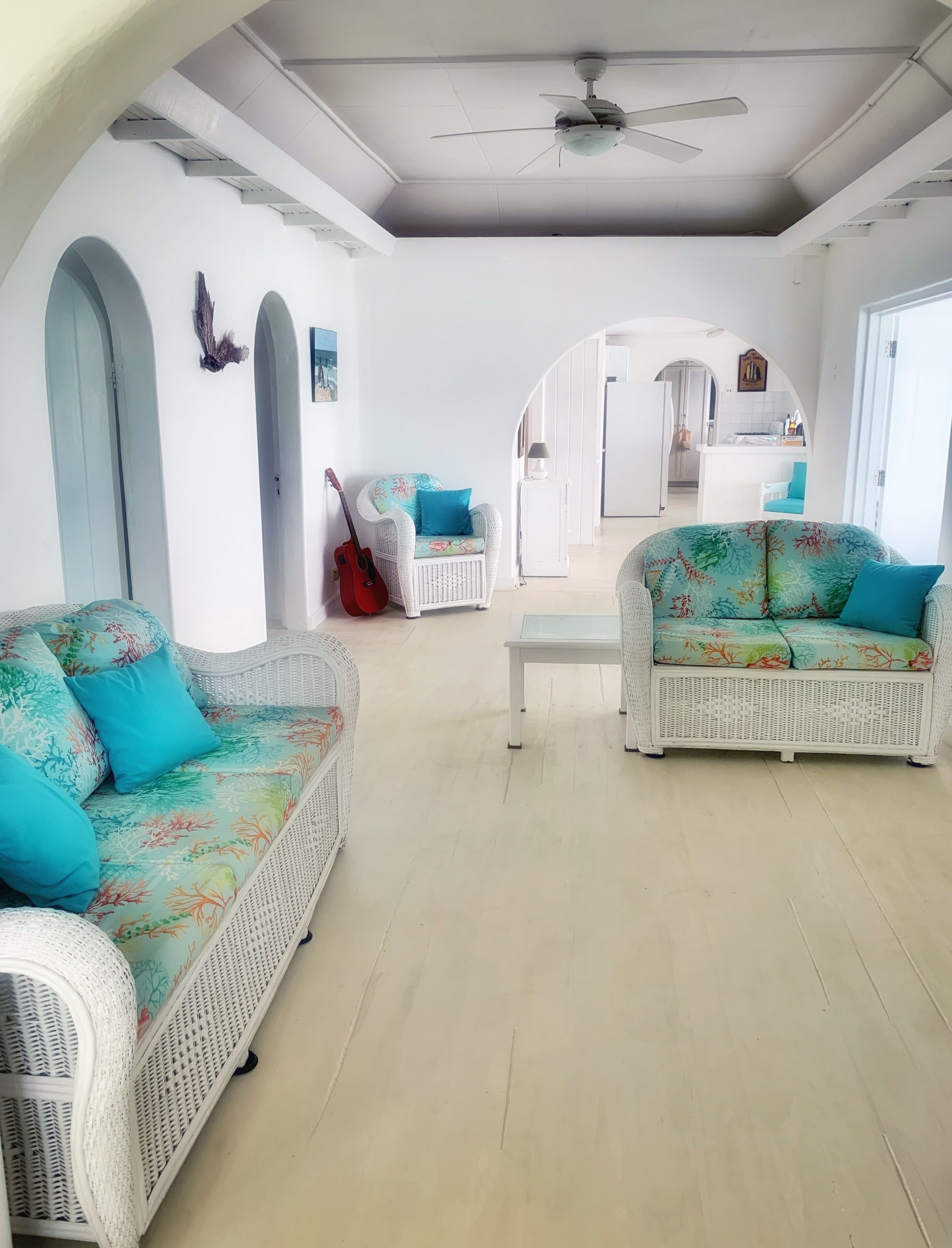The living room with wicker sofas and a guitar.
