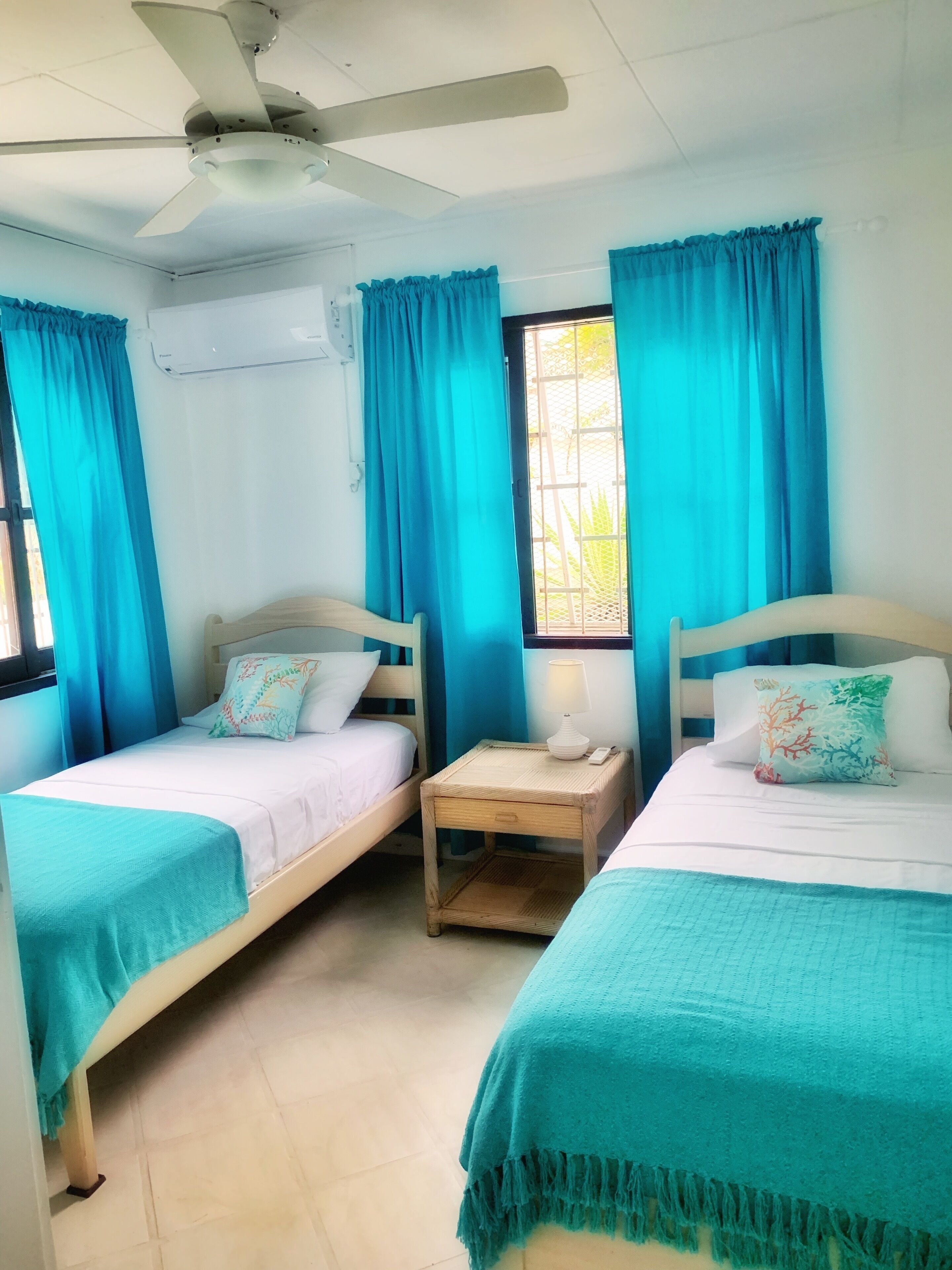 A bedroom with two single beds and turquoise curtains.