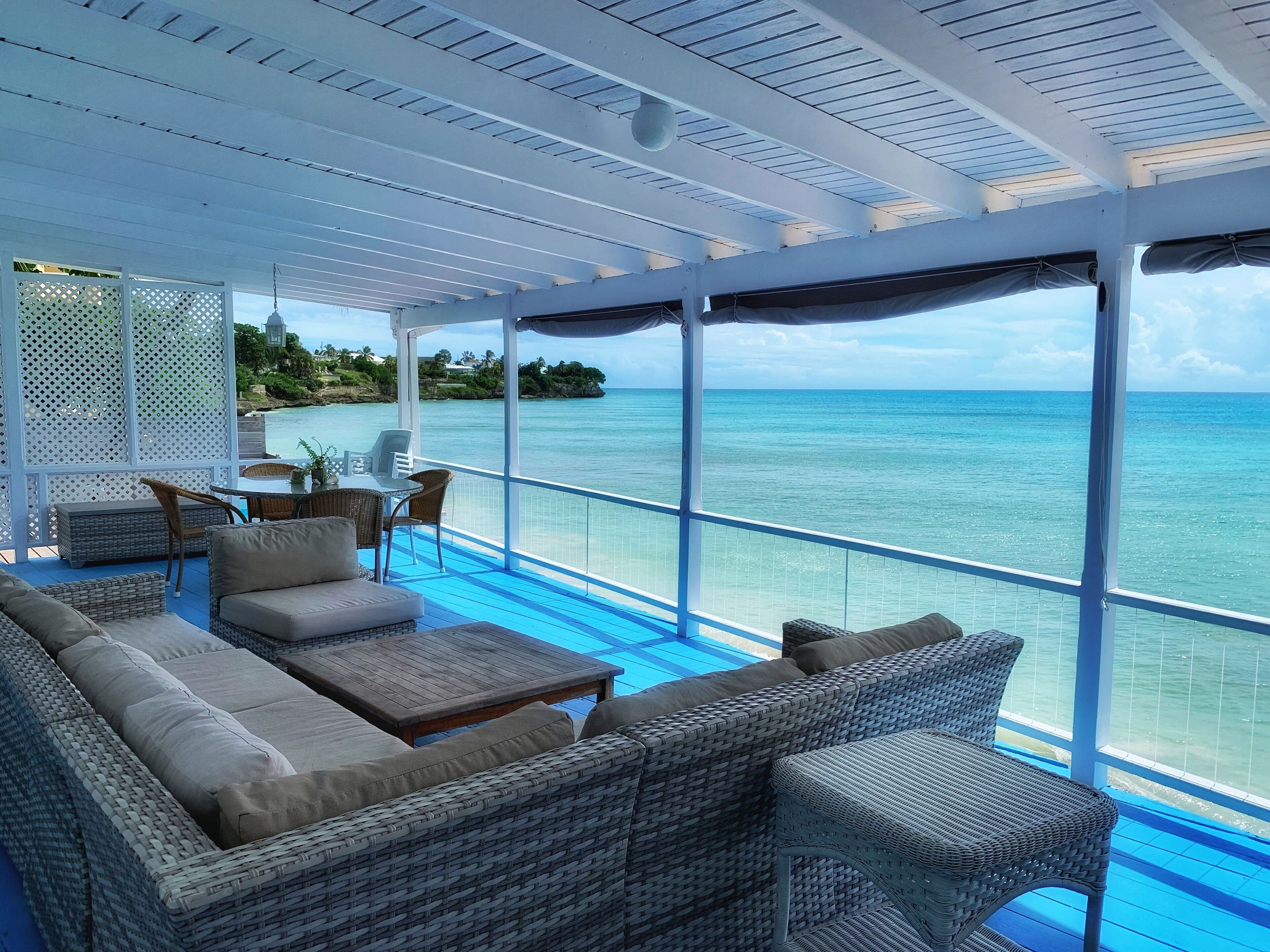 The covered veranda with sofas and a dining table, with a sea view.