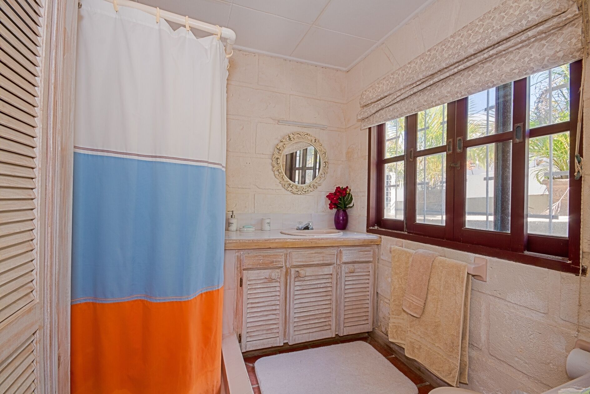 A bathroom with a sink, a mirror, and a window.