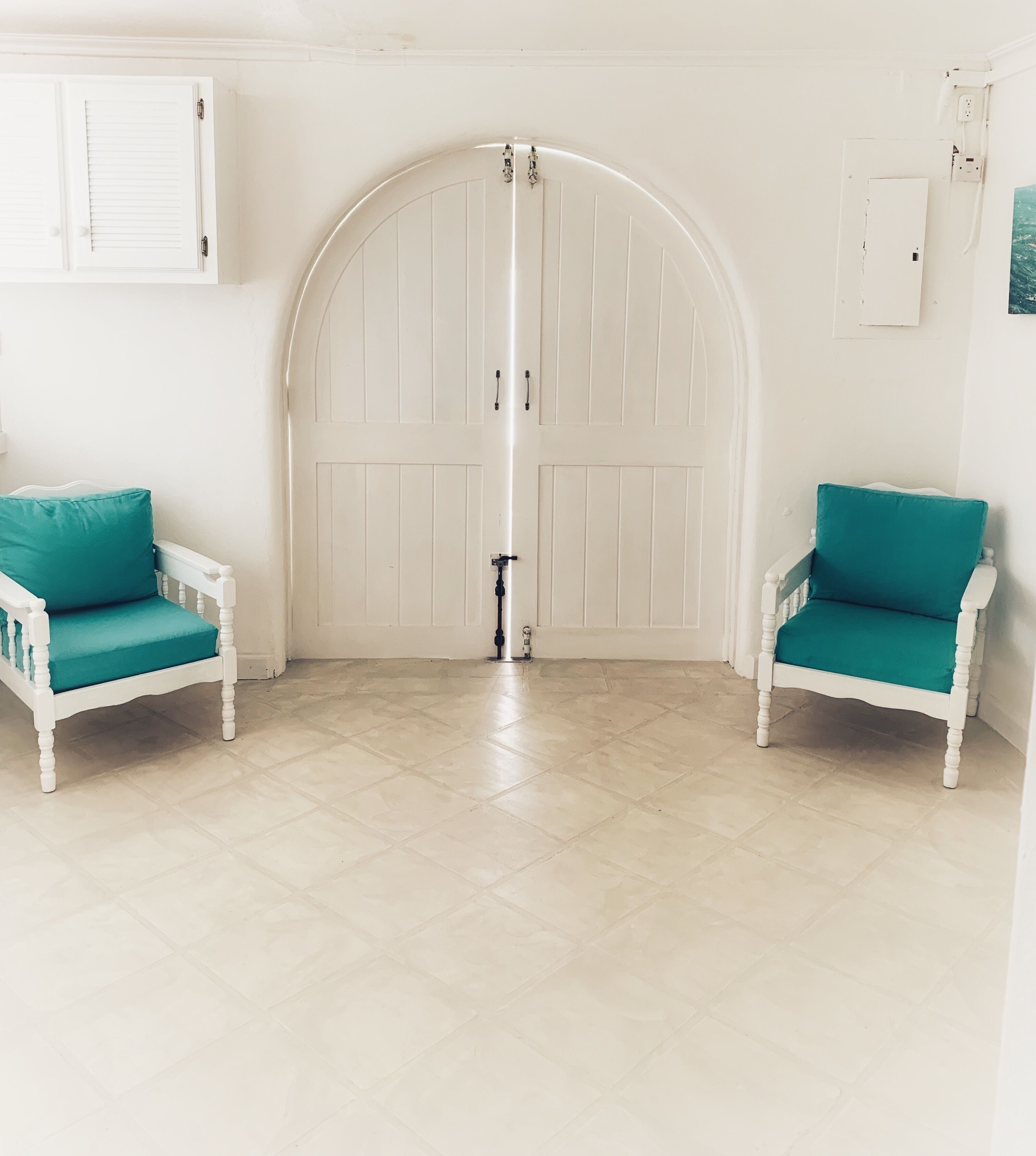 A room with arched double doors and two chairs.