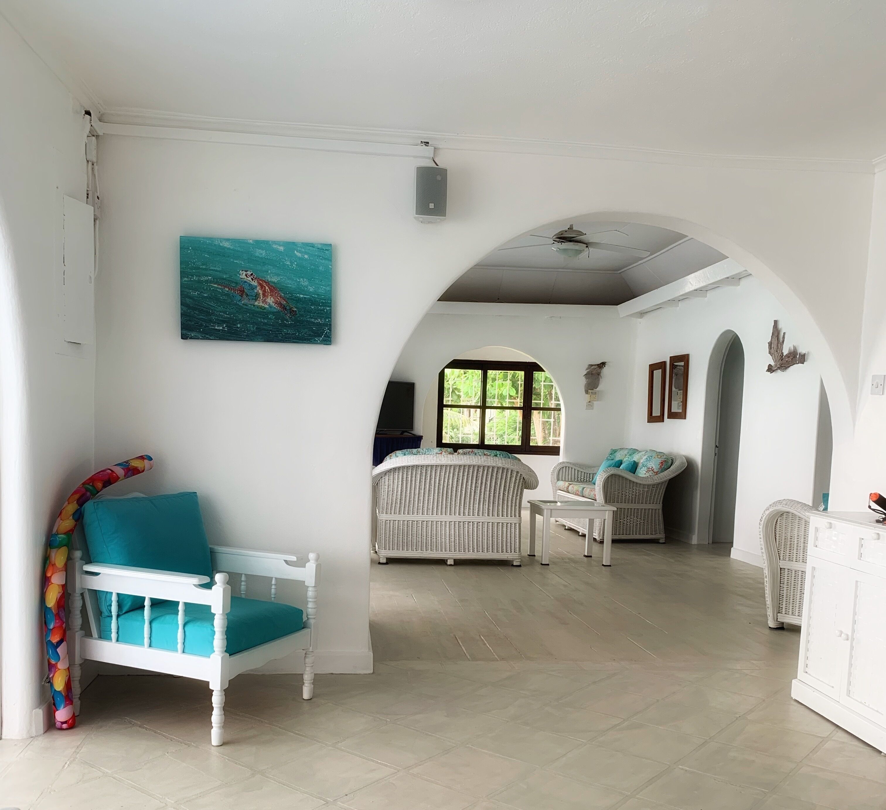 The living room with wicker seats and a turtle painting.