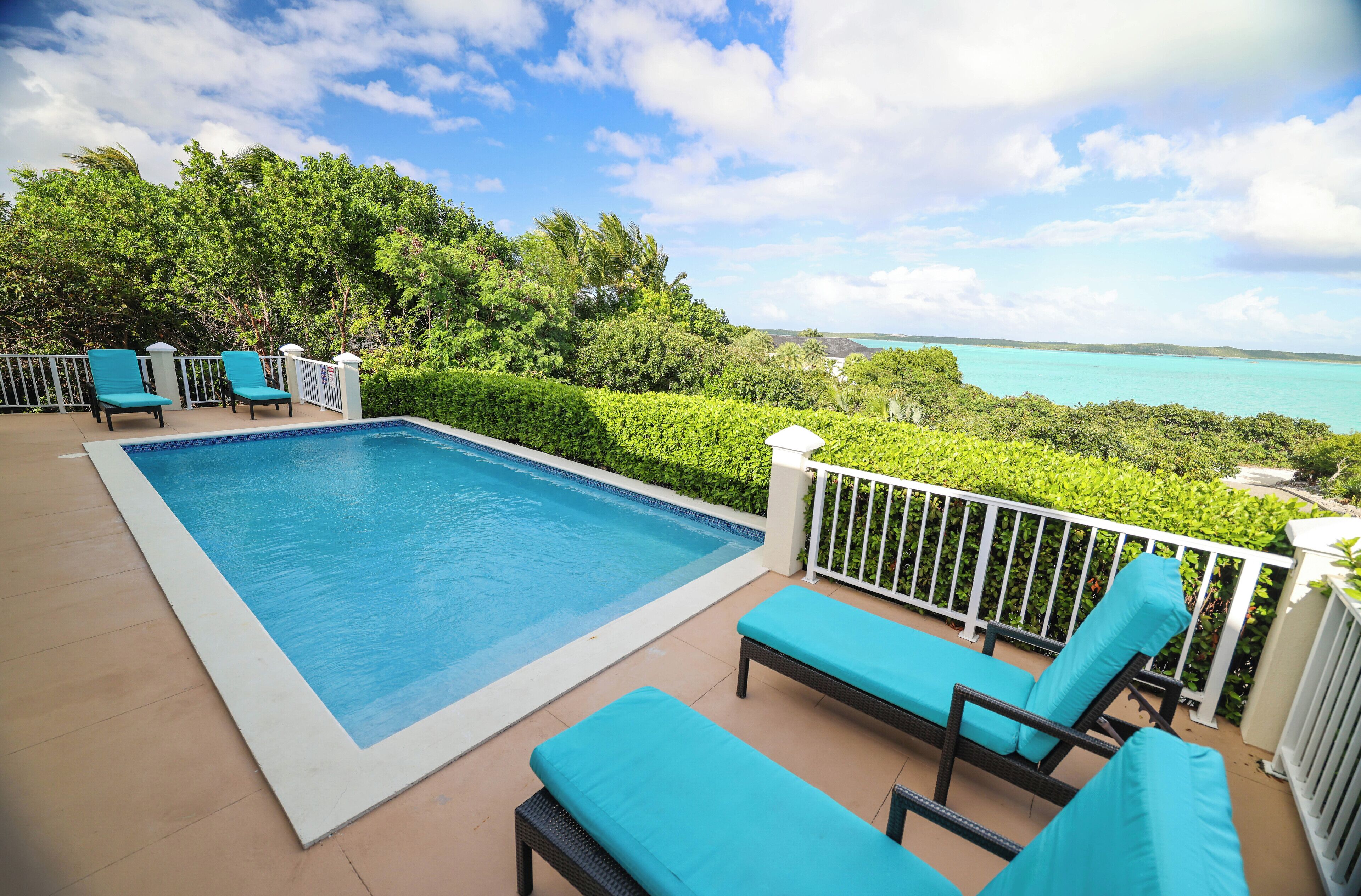 The pool with loungers and the turquoise sea behind it.
