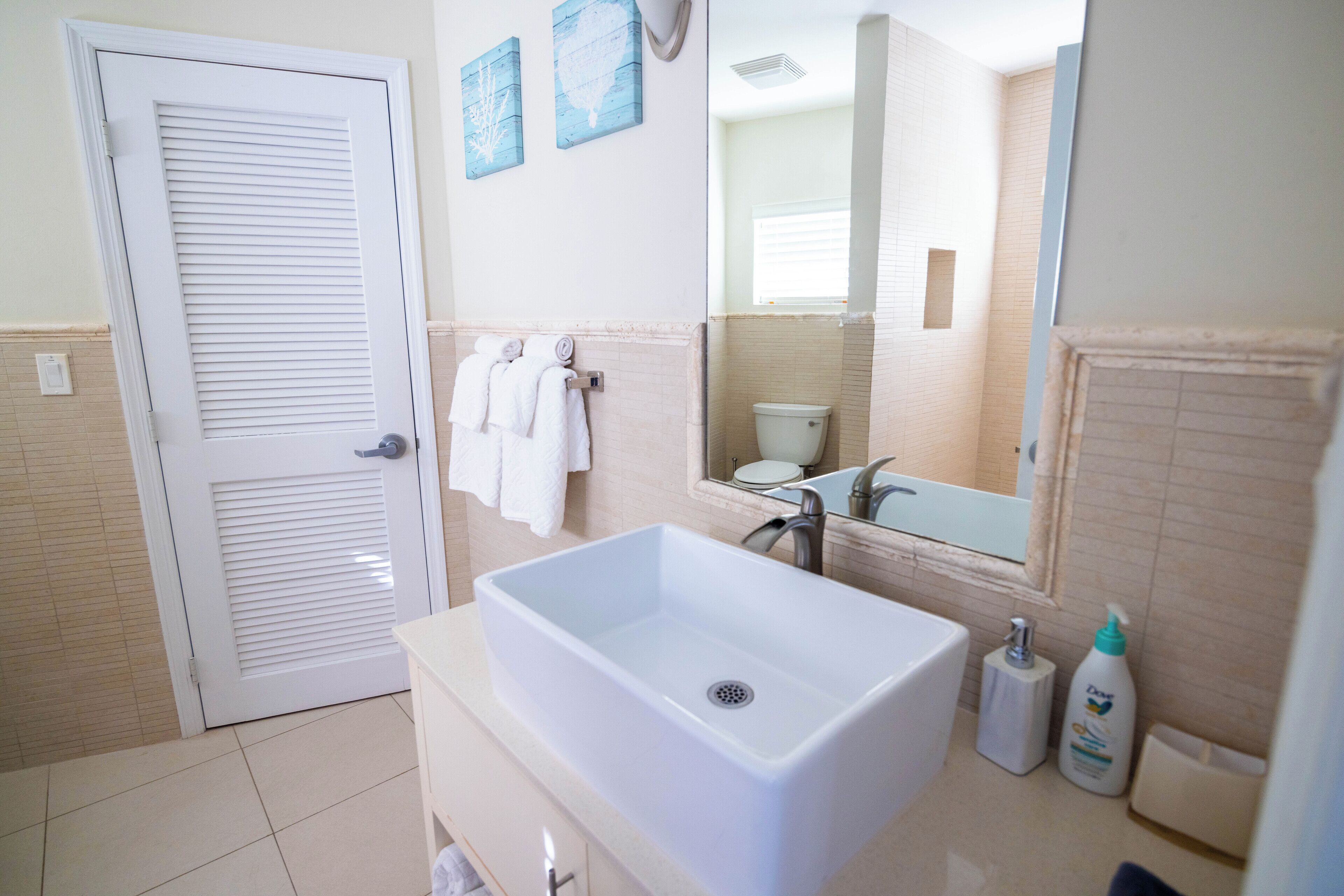 A bathroom with a white basin, a mirror, and towels.