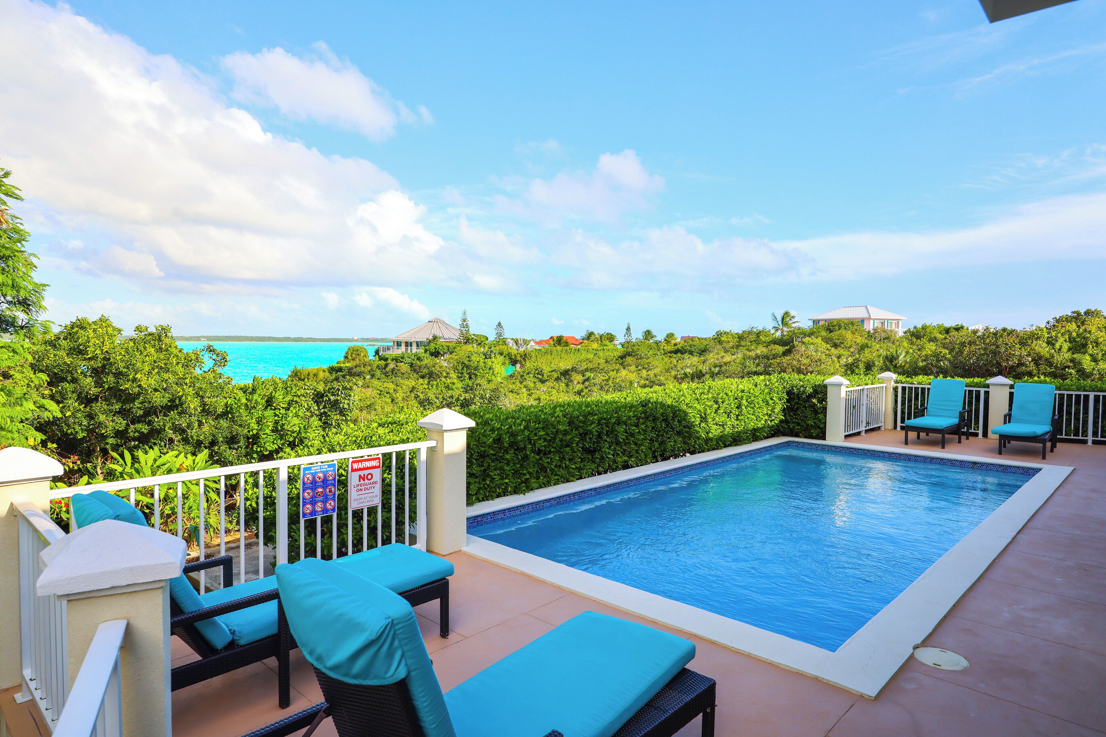 The pool with loungers and a view of the turquoise sea.