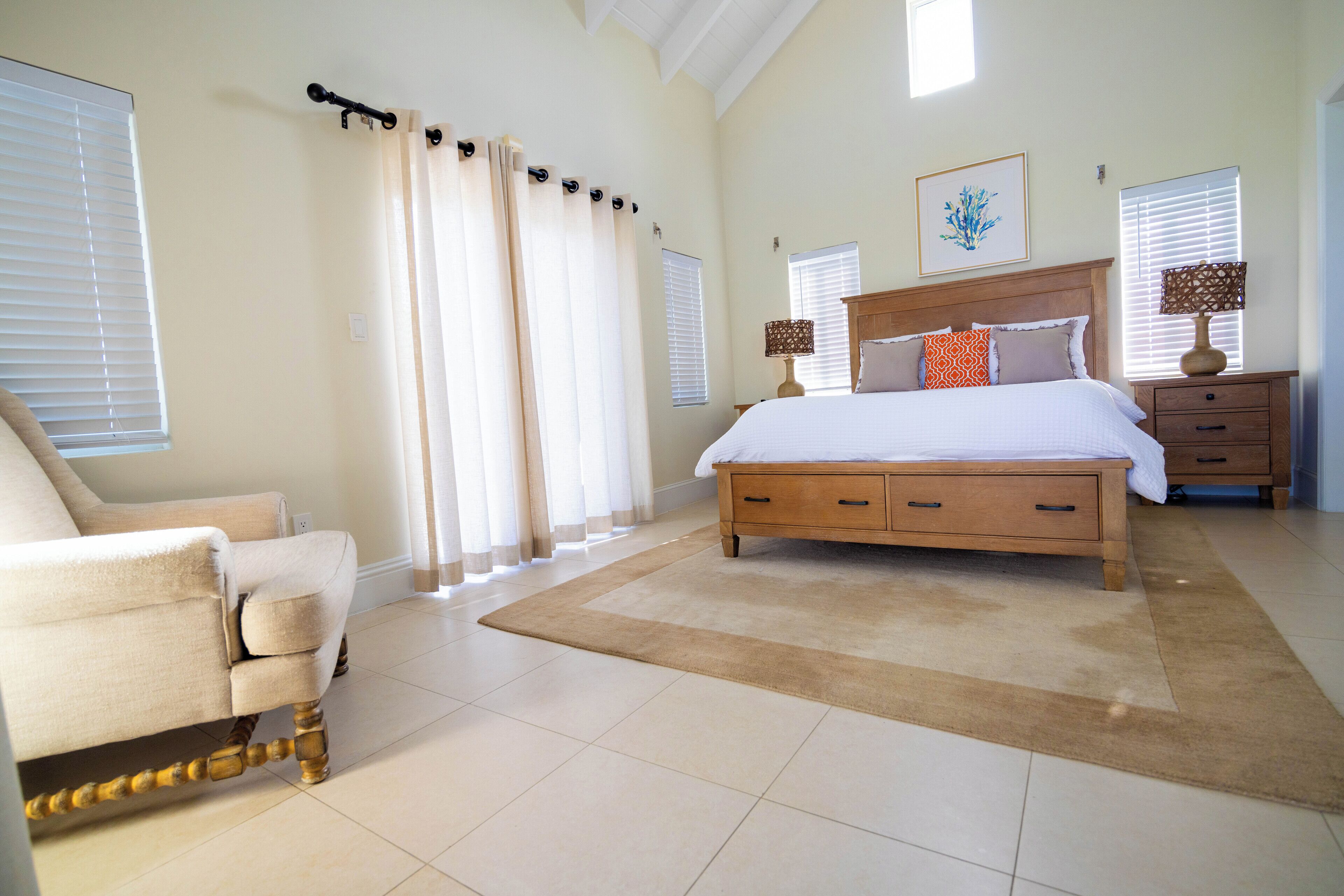 A bedroom with a wood bed, an orange pillow, and two lamps.