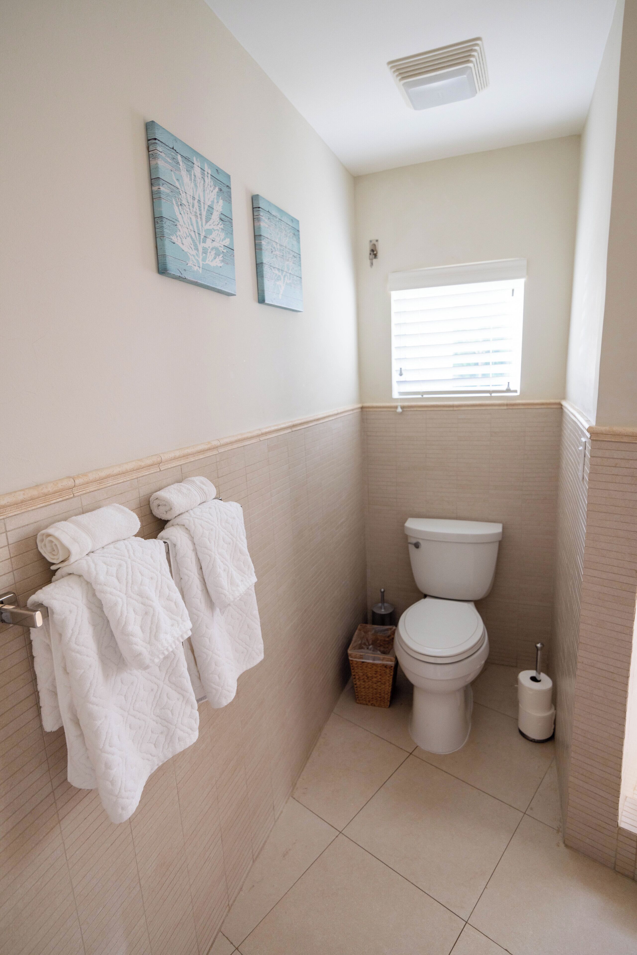 A toilet room with towels on a rail and a small window.