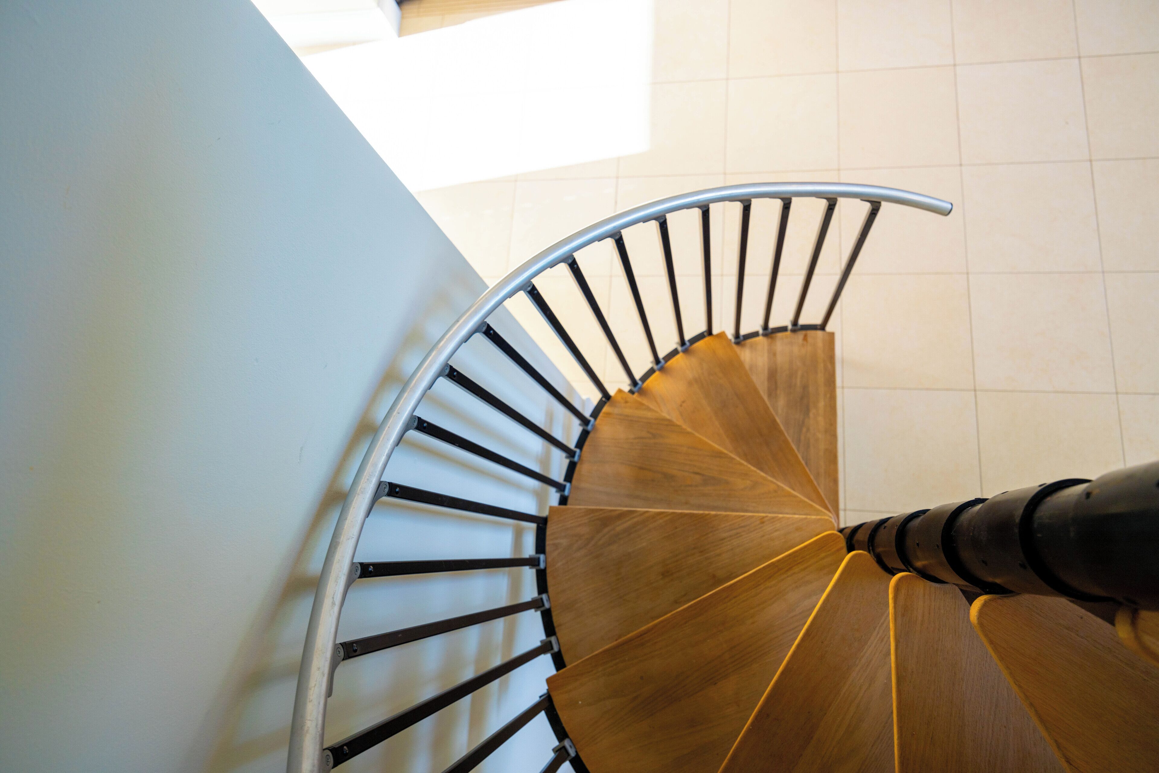 A spiral staircase with wood steps, seen from above.