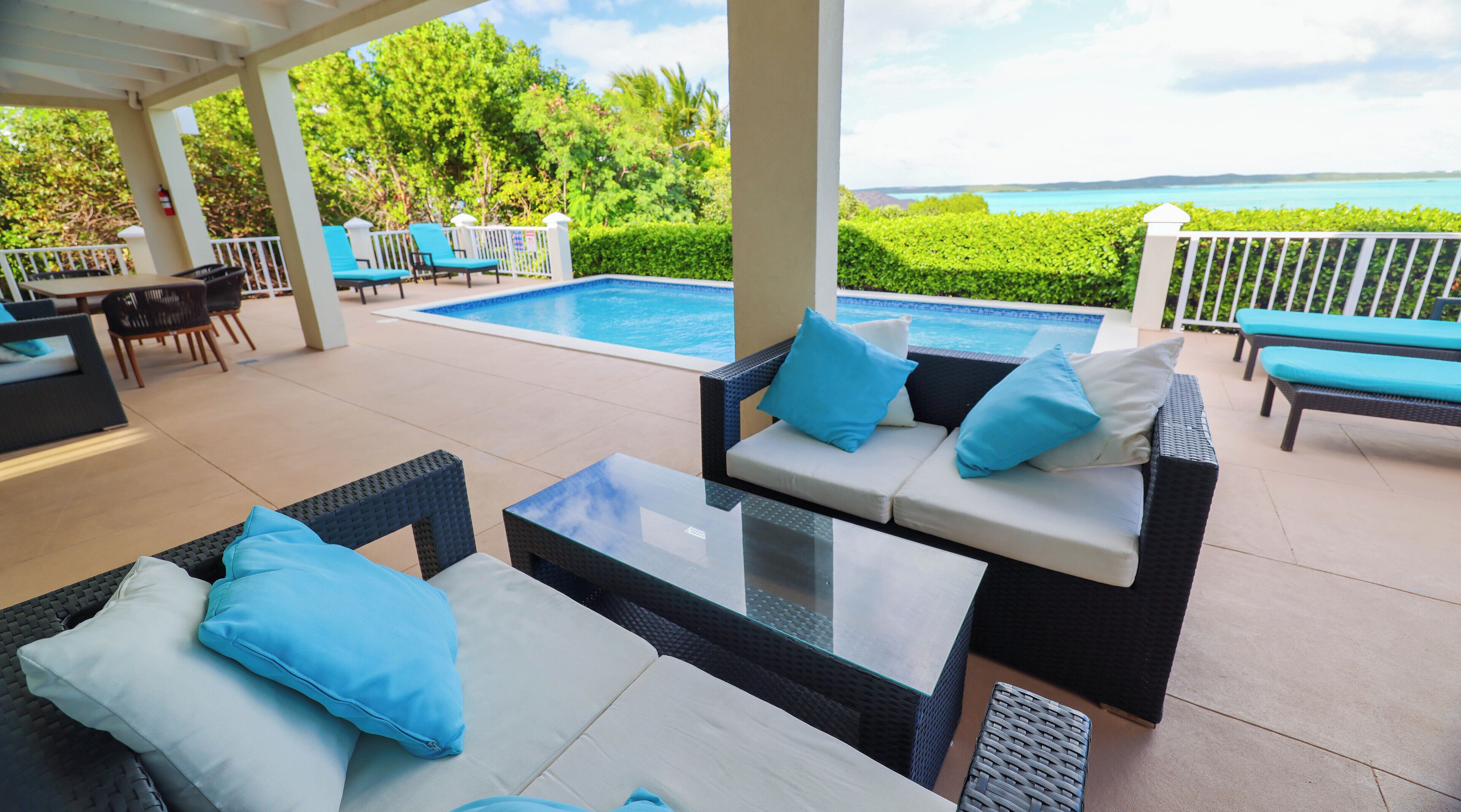 The covered terrace with sofas, the pool, and the sea view.