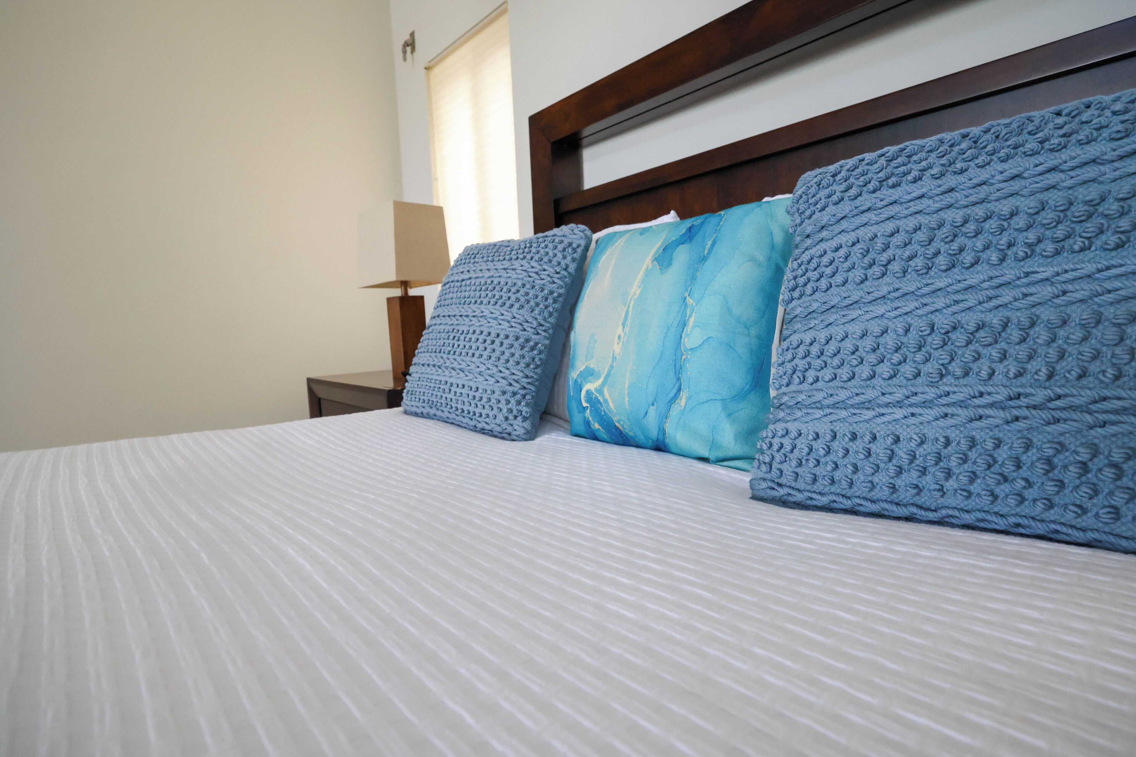 Blue pillows on a bed with a dark wood headboard.