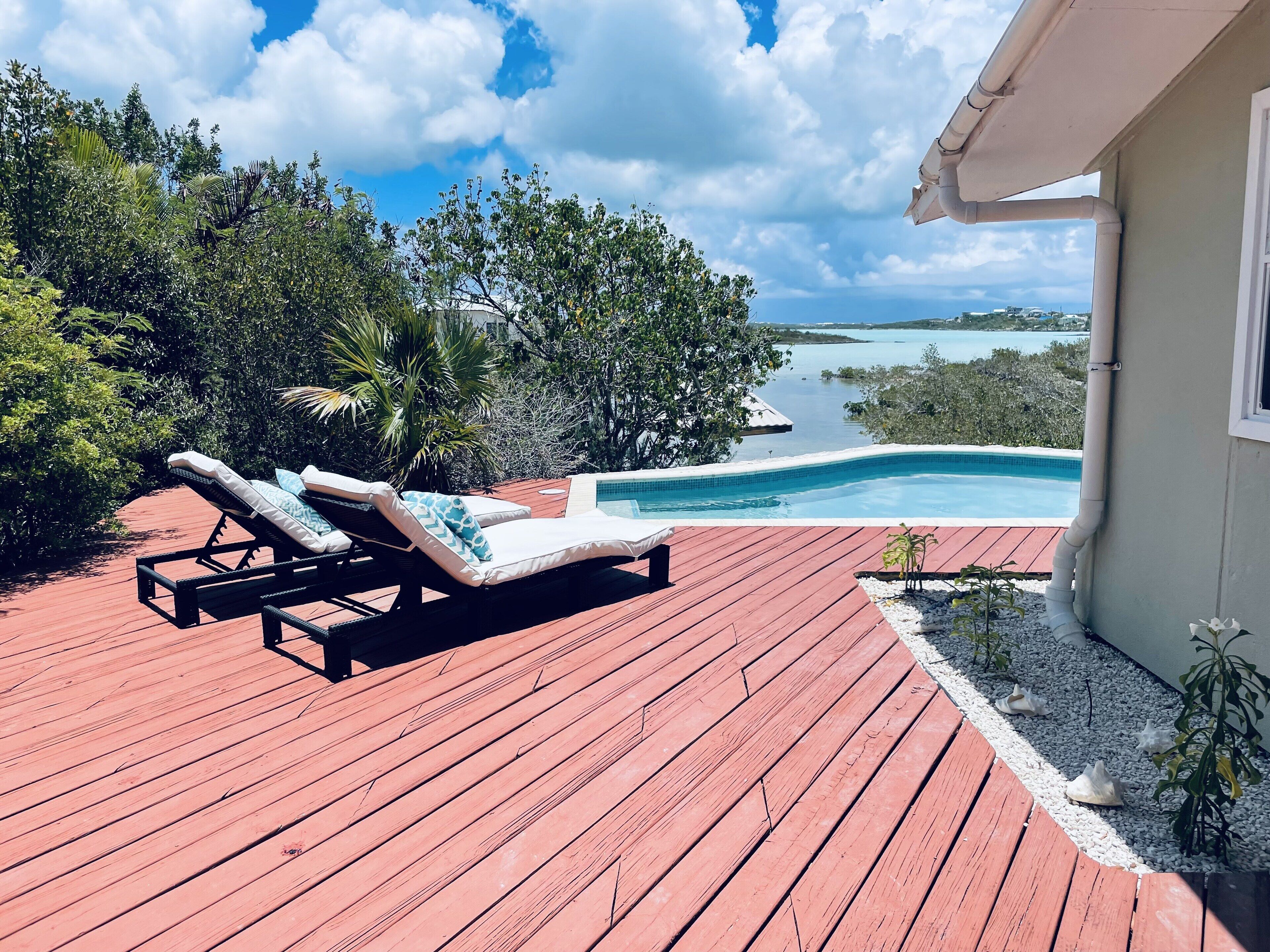 Two loungers on the deck next to the pool, with a view of the turquoise water.