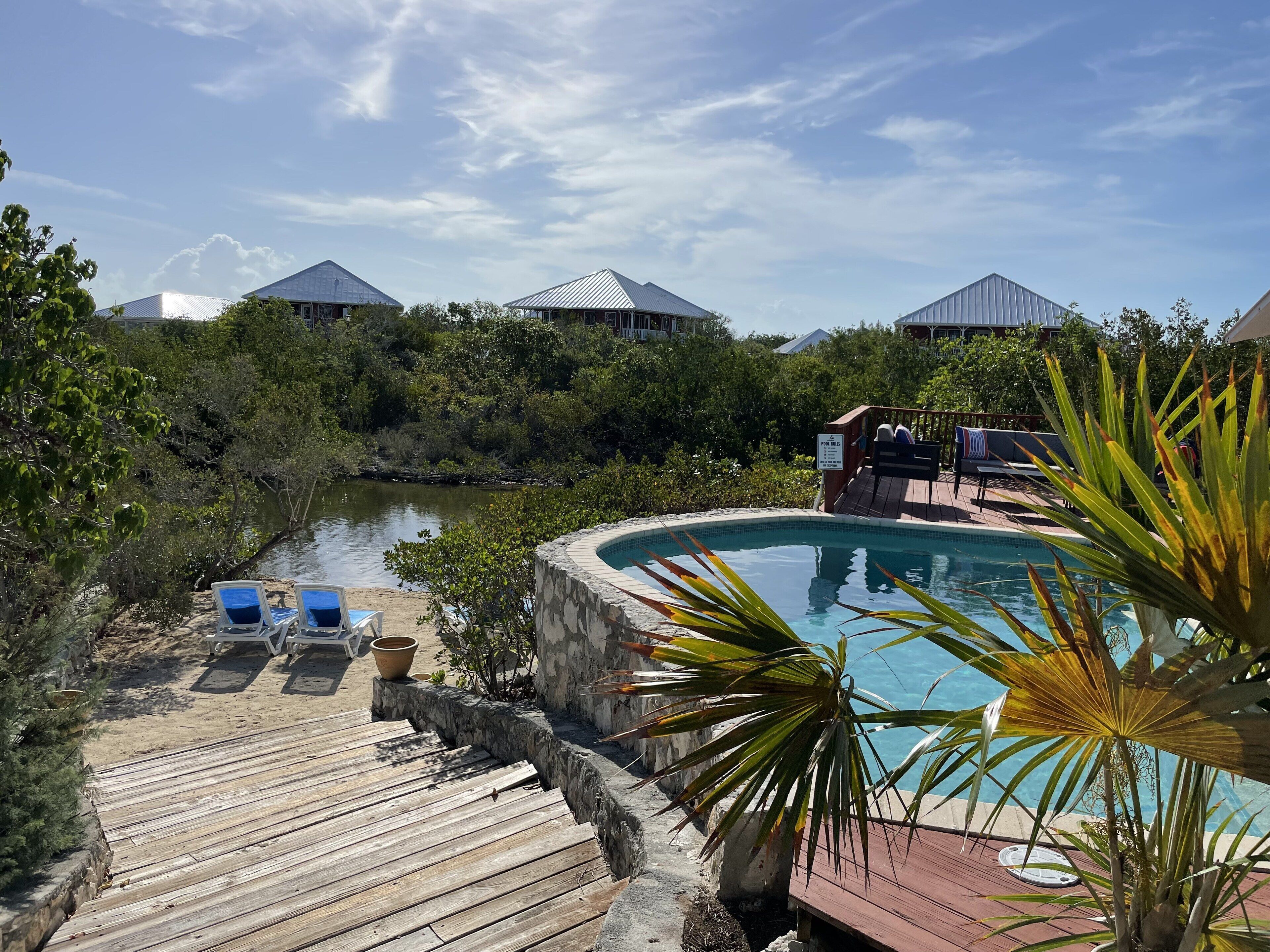 The pool, a sand area with two chairs, and a wood walkway.