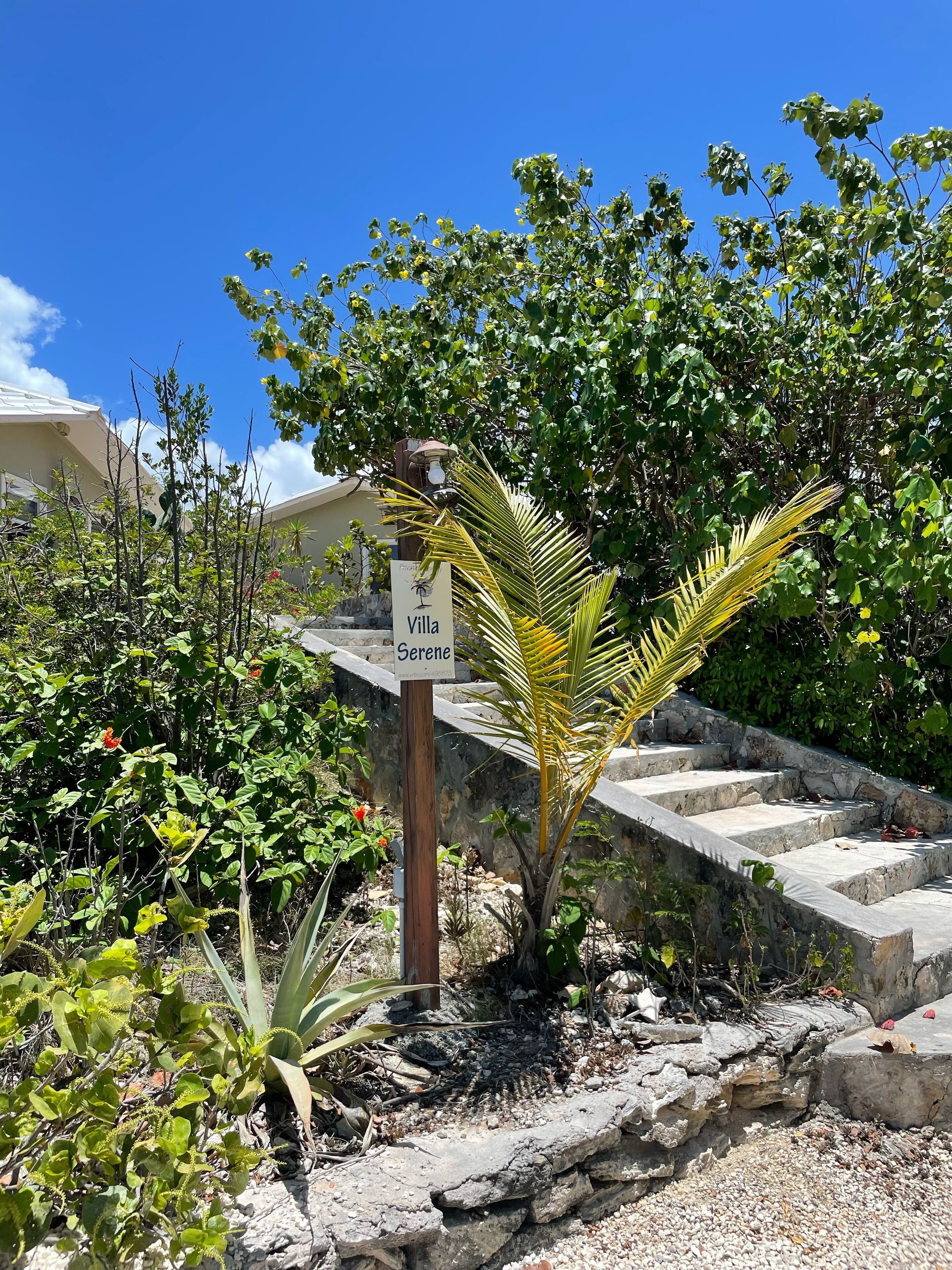 Stone steps and a post with the villa sign next to plants.
