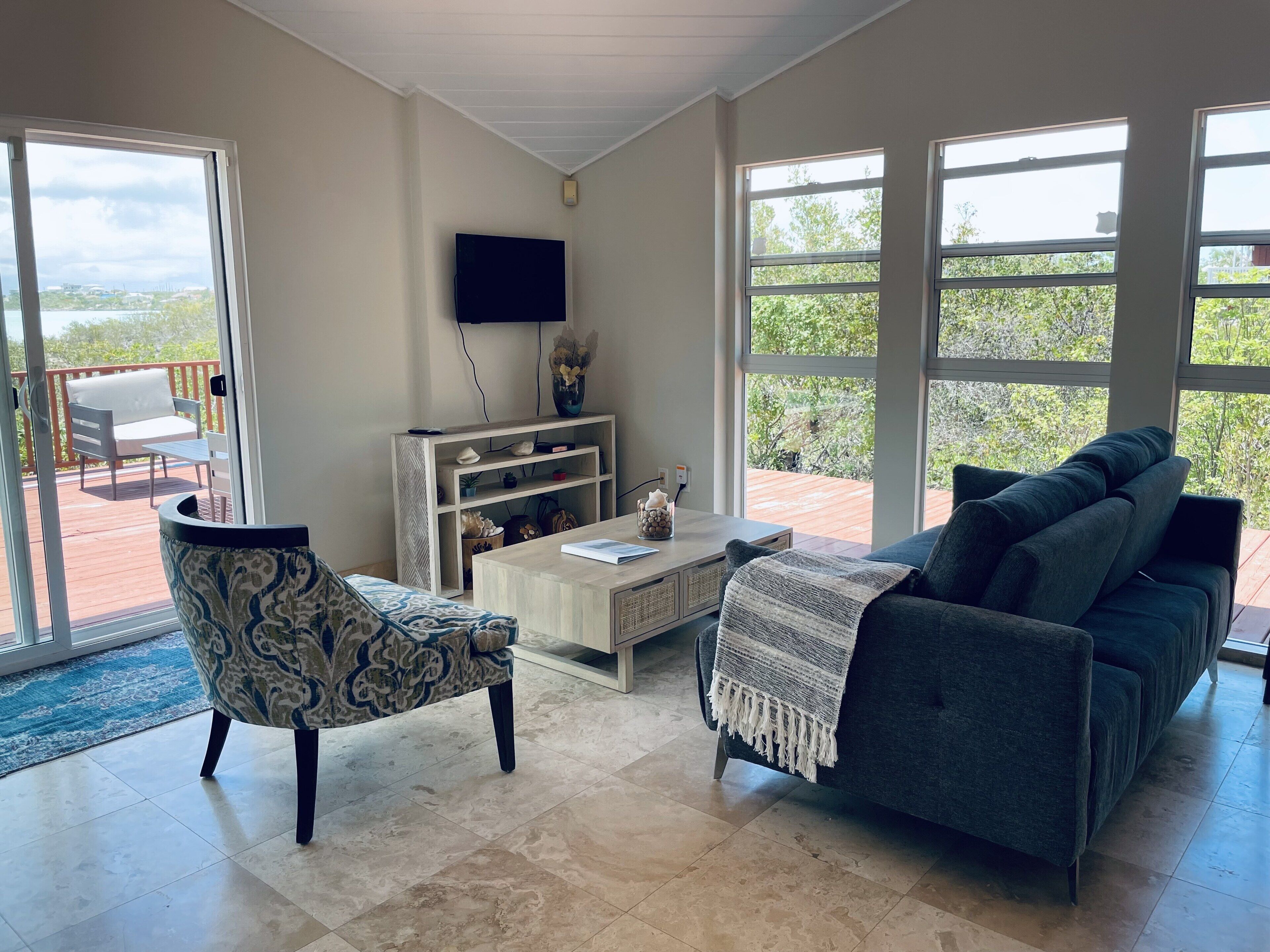 A living room with a sofa, an armchair, a low table, and a television.