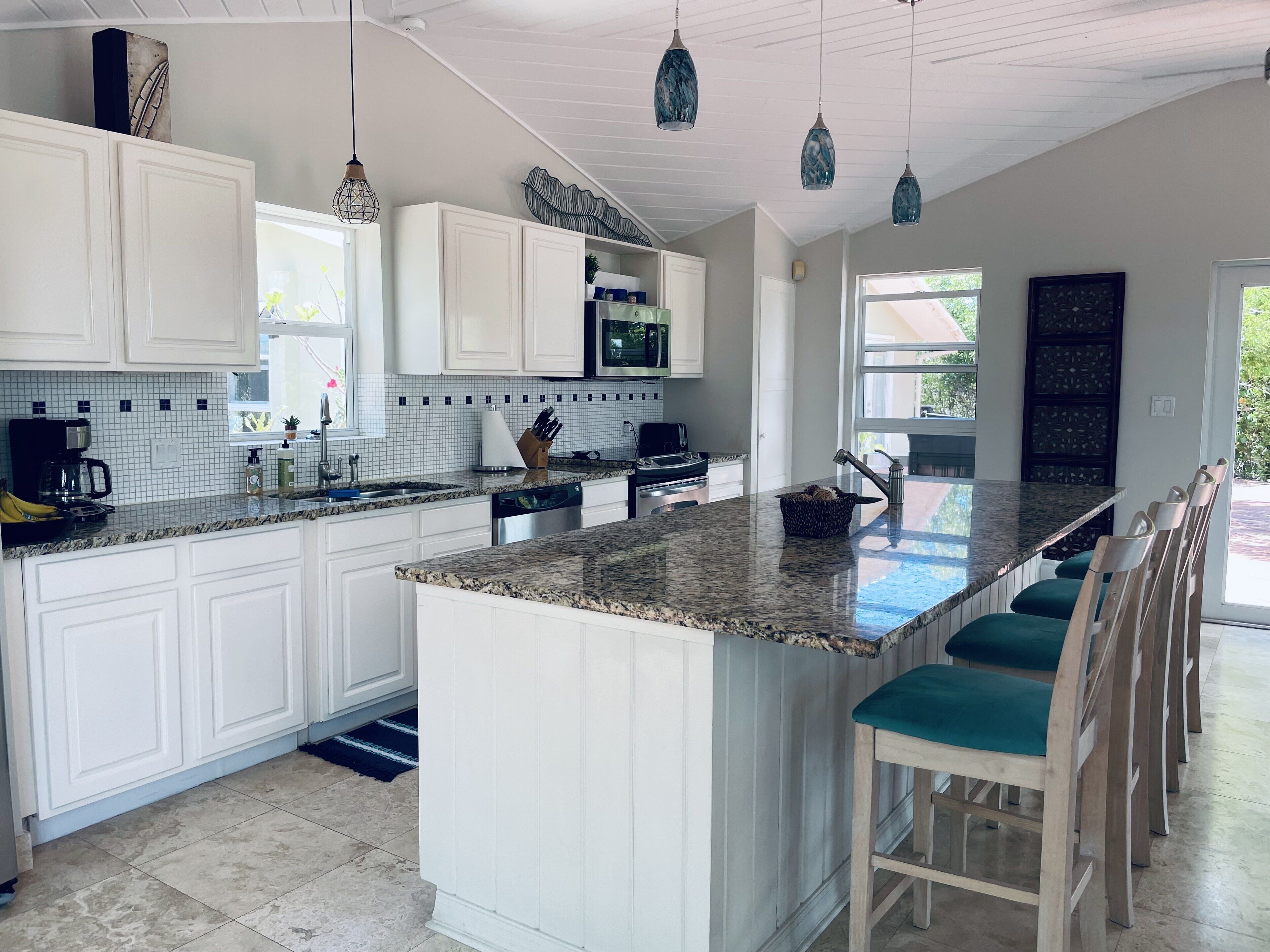 A kitchen with white cabinets, a granite counter, and stools at an island.