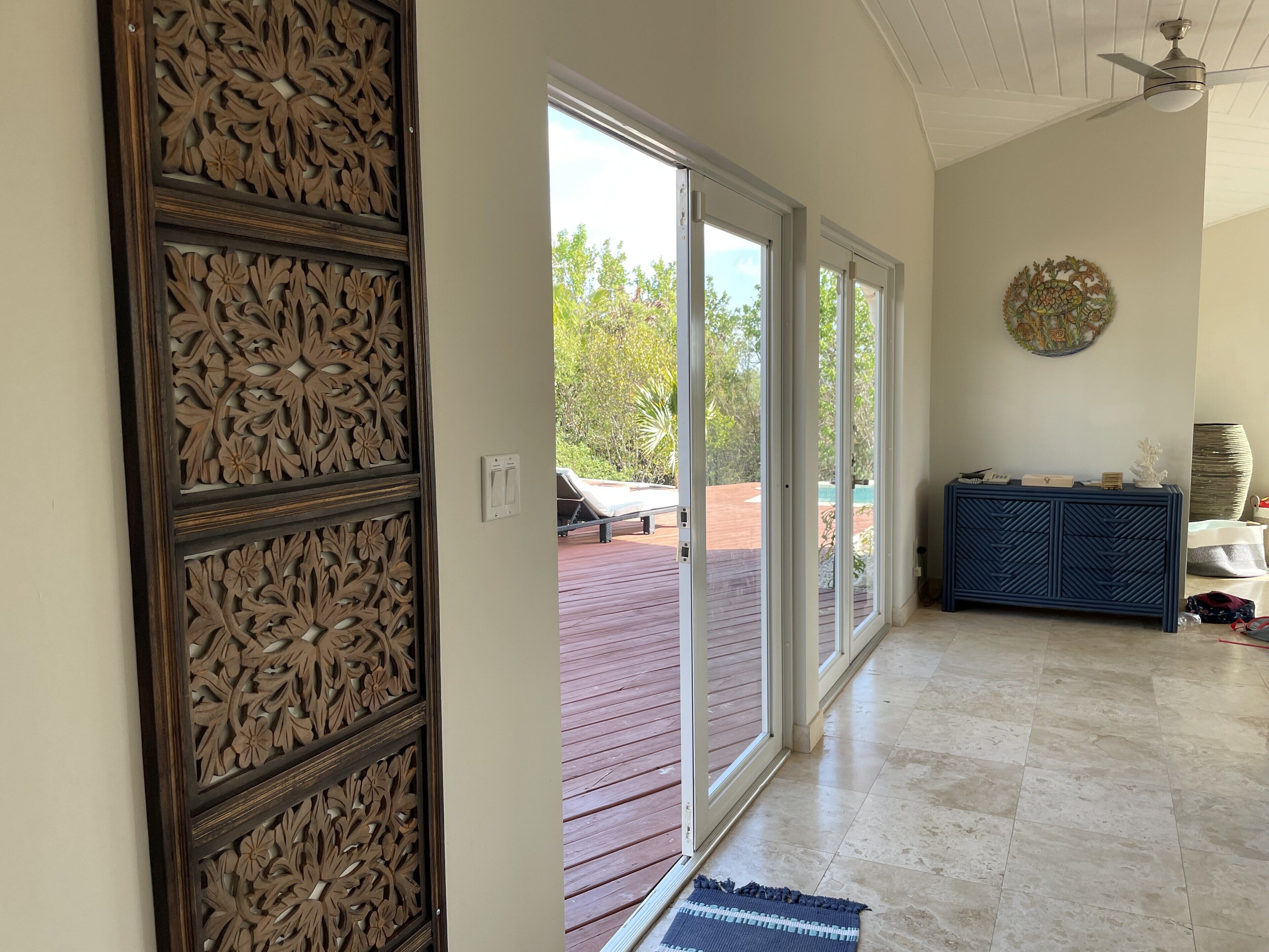 A hallway with a carved wood panel and glass doors to the deck.