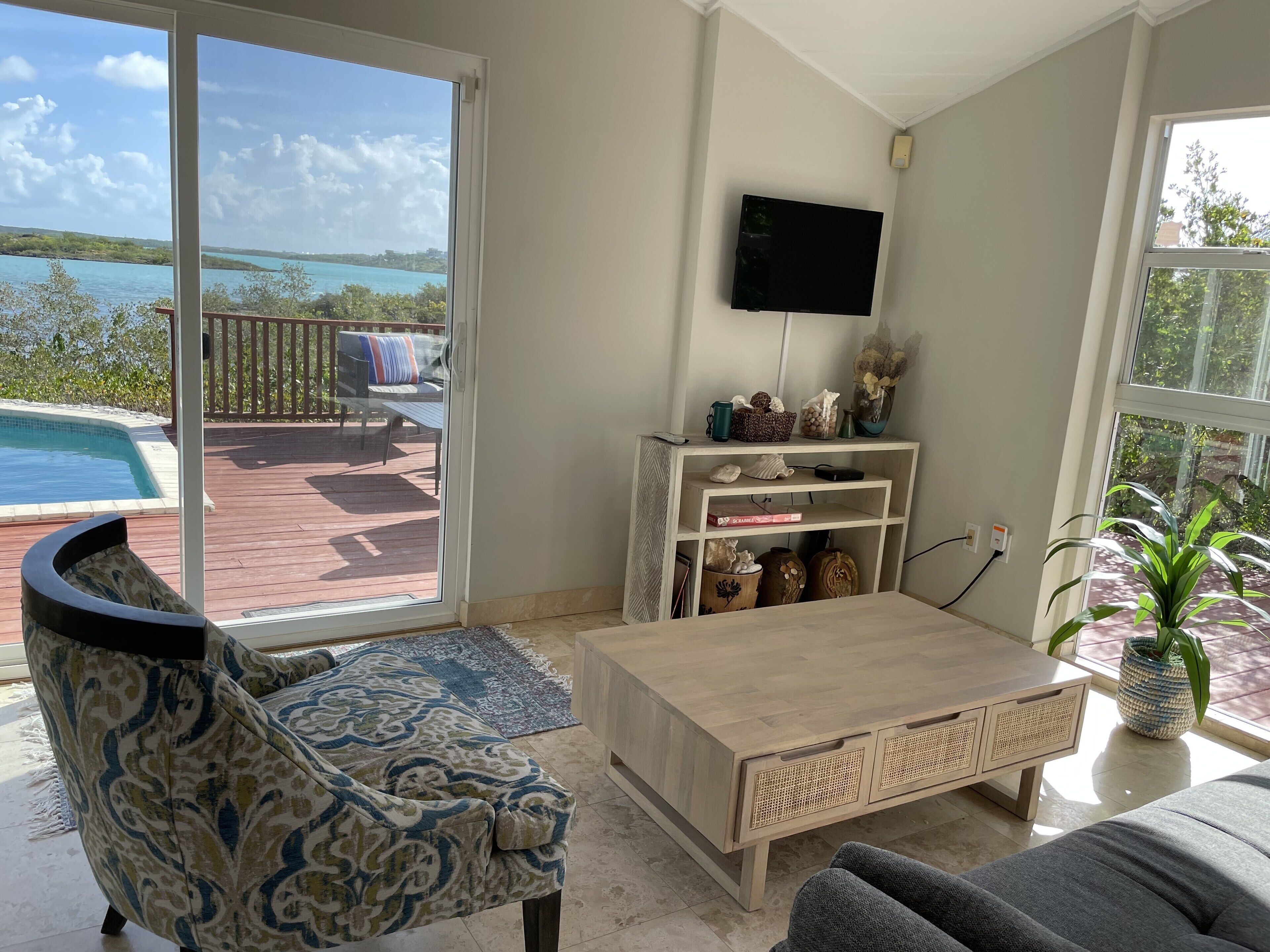 A living room with an armchair and a glass door with a view of the water.