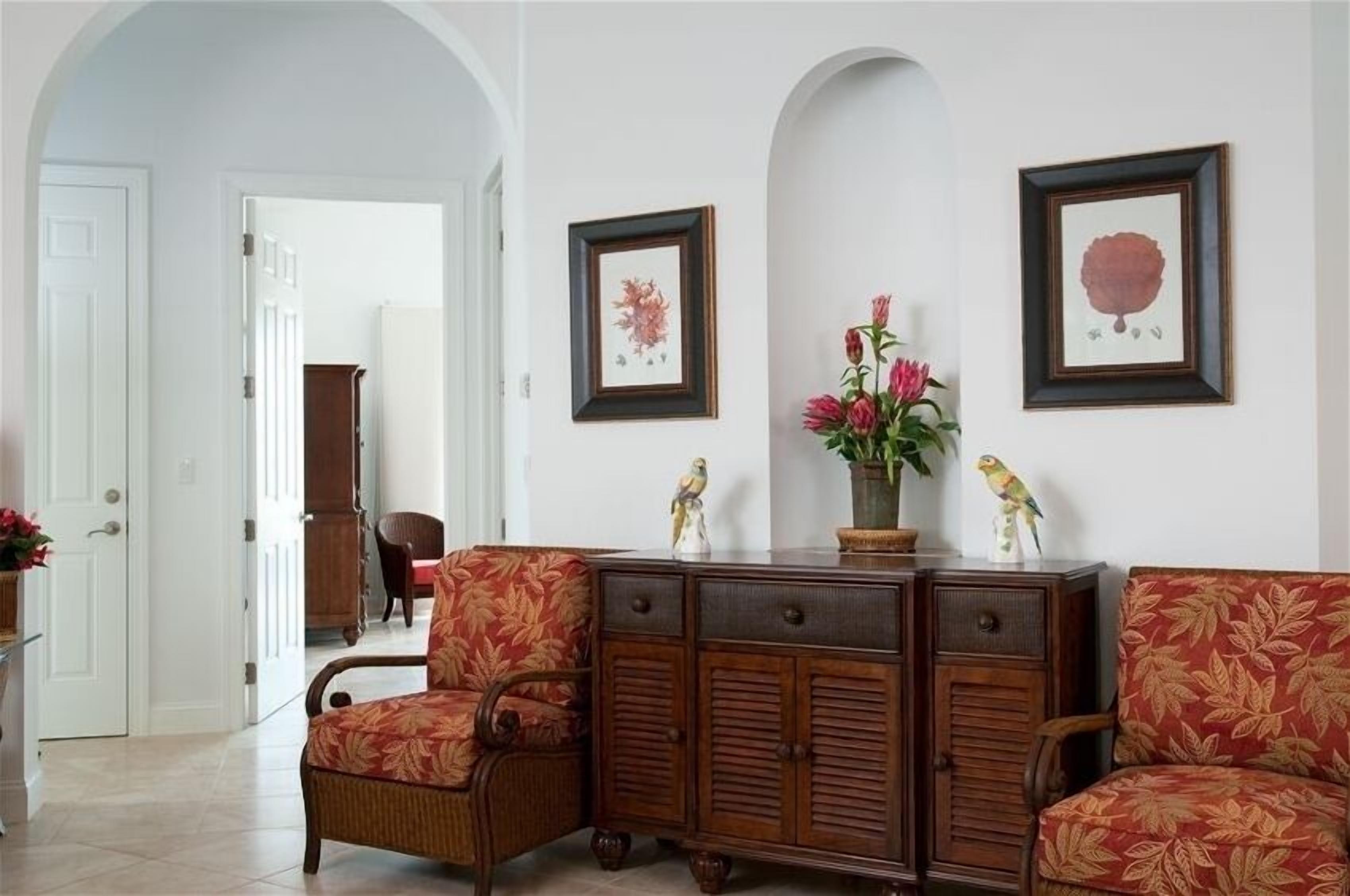A sitting area with two armchairs and a wood sideboard.