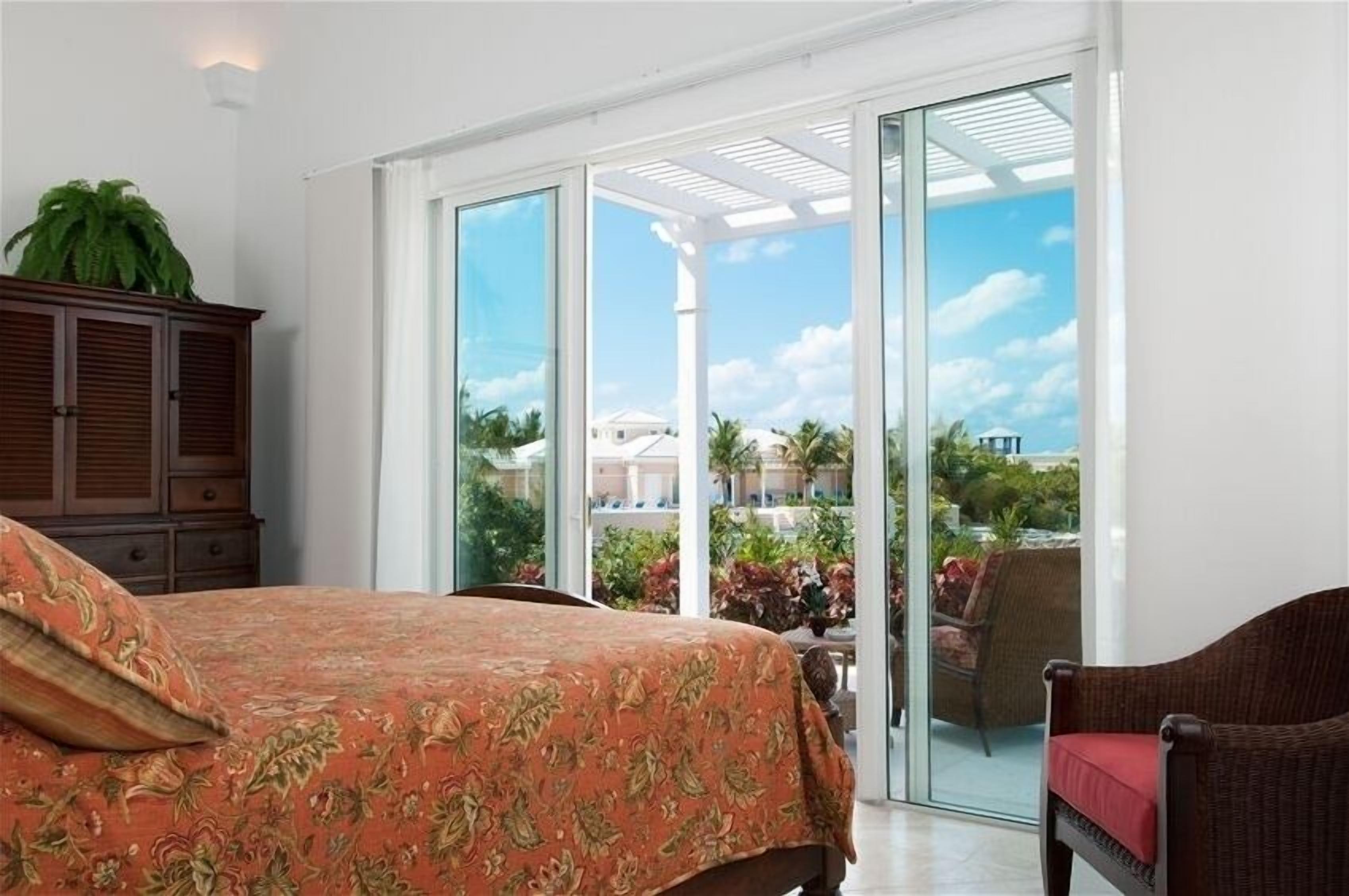 A bedroom with a floral bedspread and doors to a terrace.