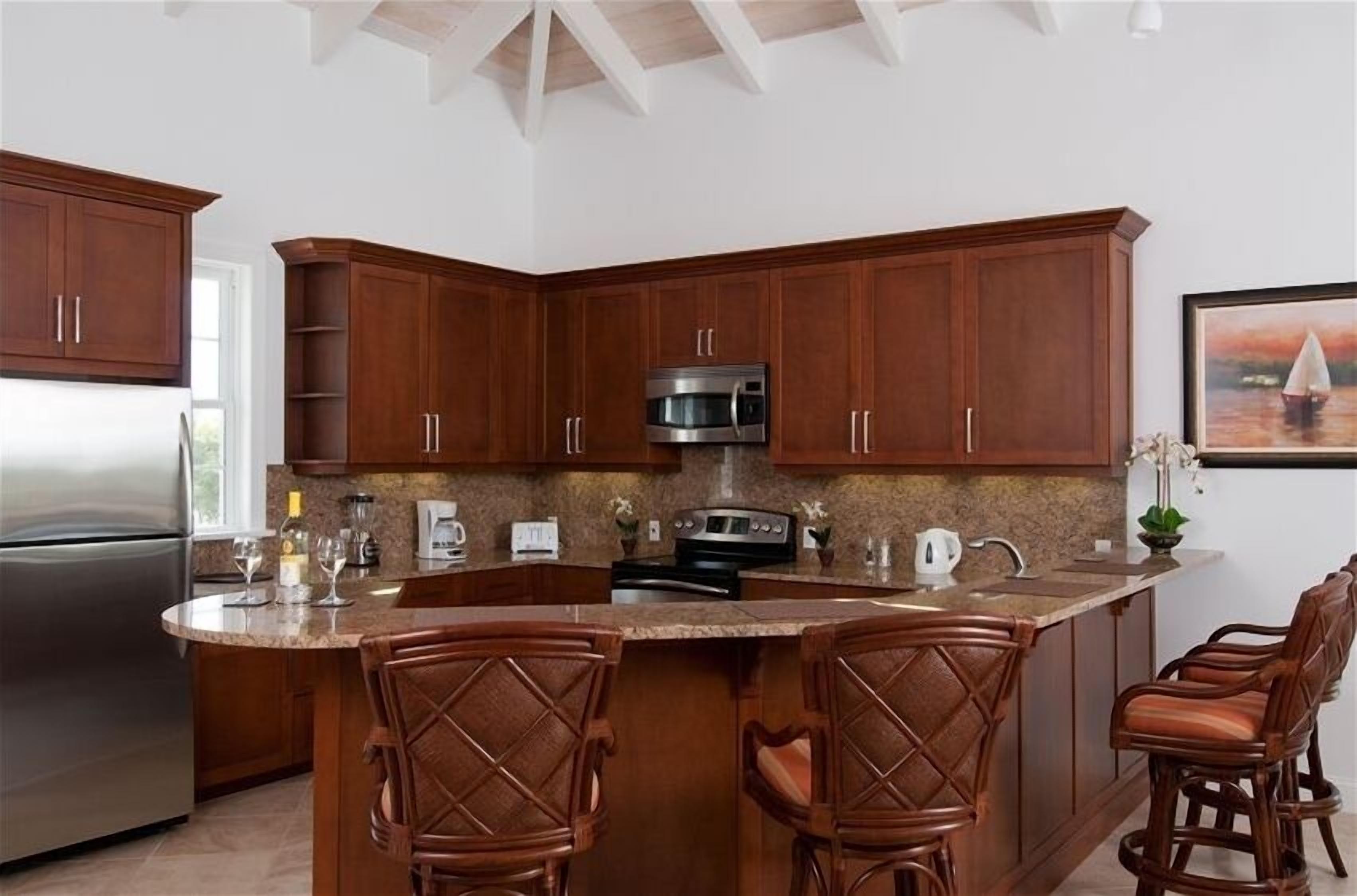 The kitchen with a bar counter and bar stools.