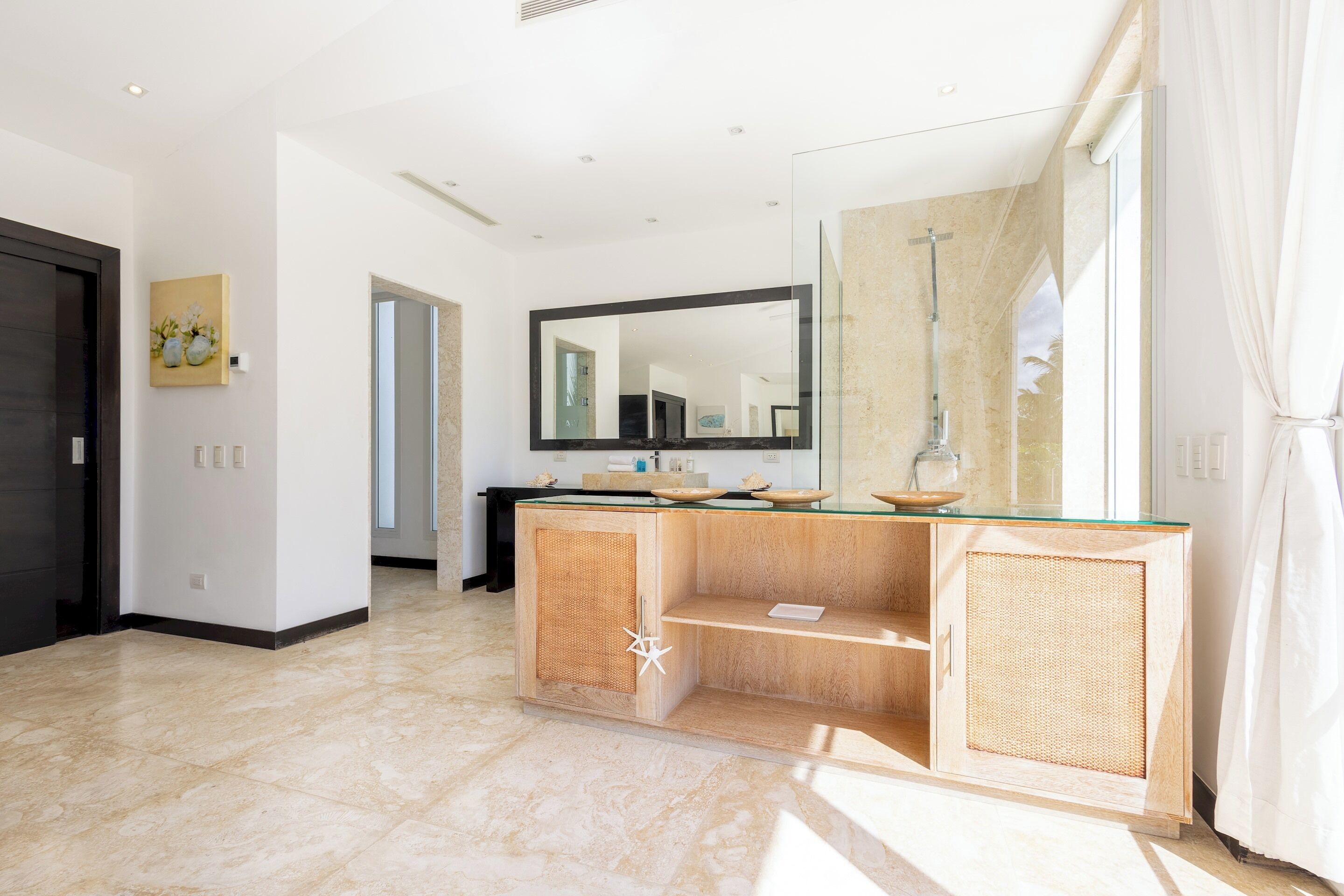 The bathroom has a wooden cabinet, a large mirror, and a shower behind a glass panel.
