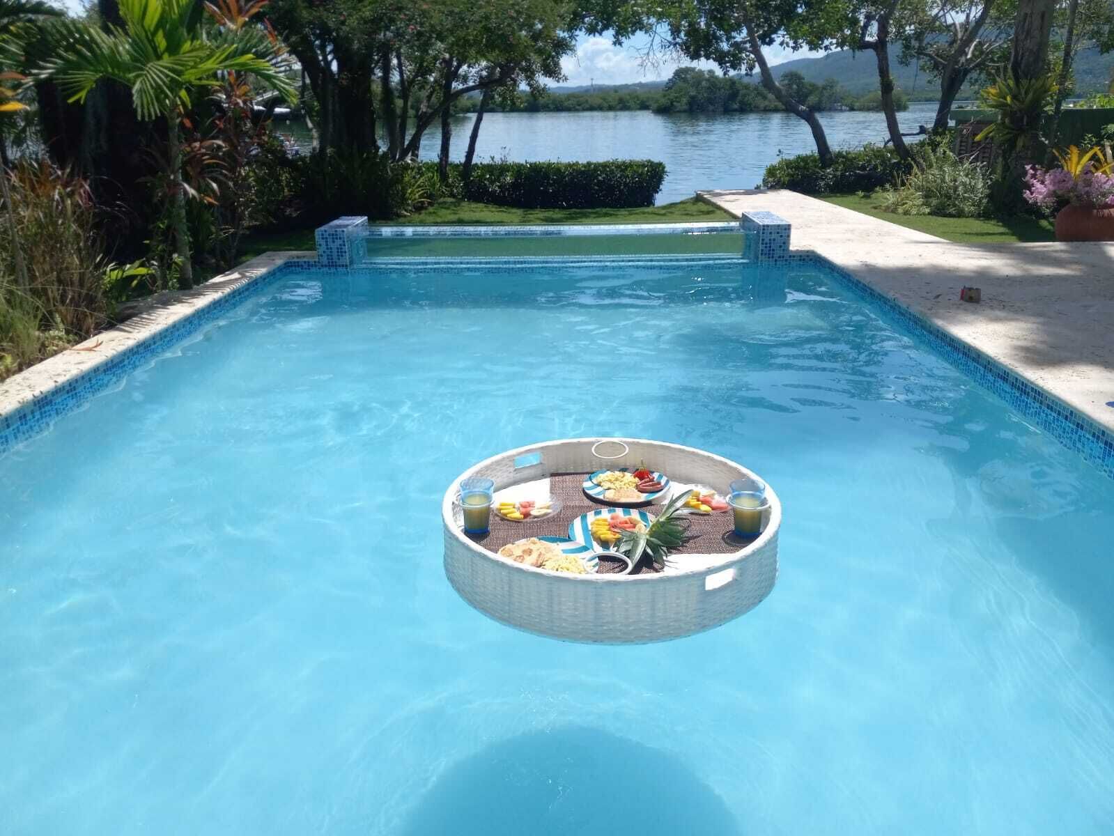 A breakfast tray floats in the pool beside the bay.