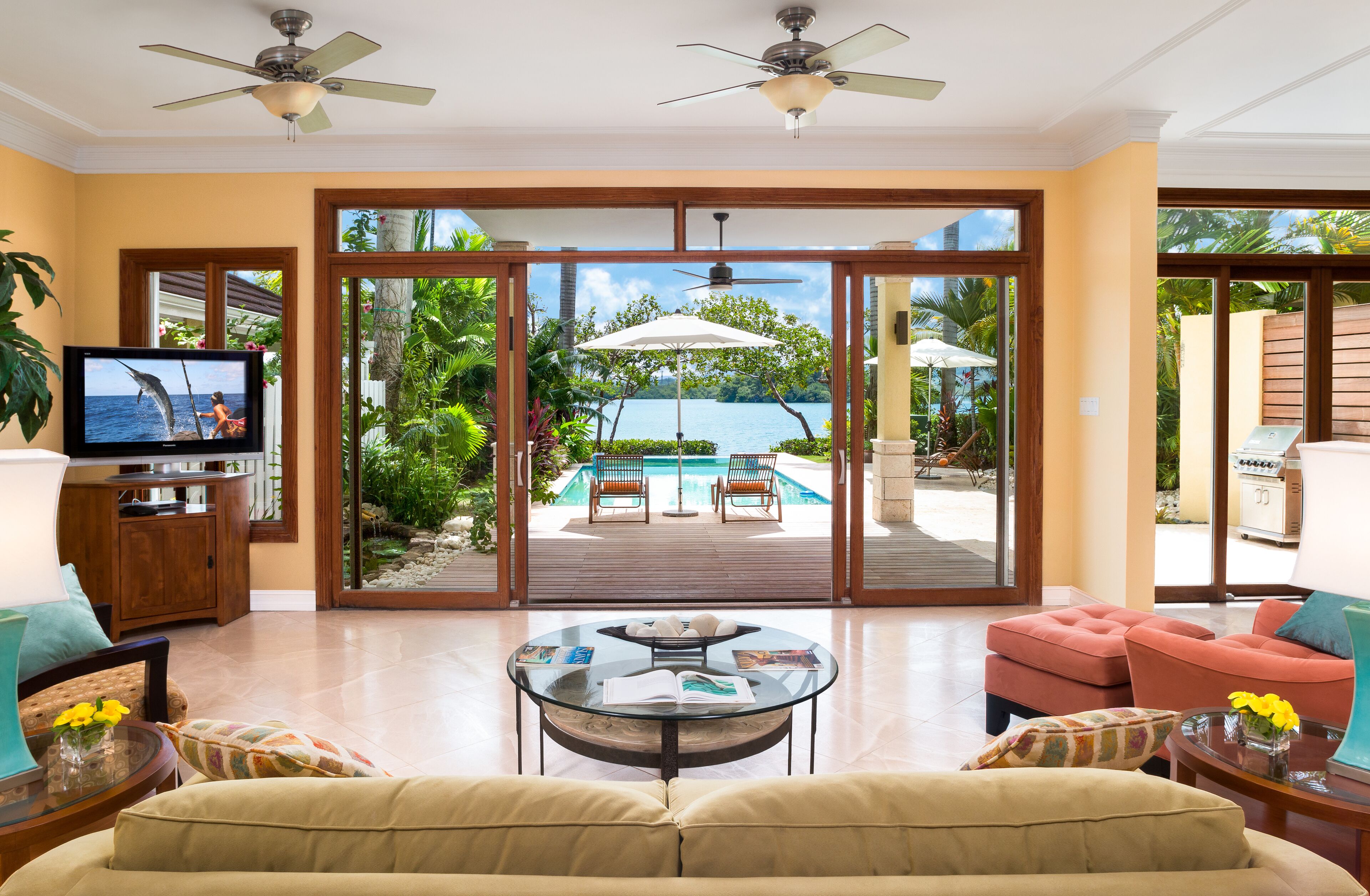 A living room with open doors to the pool deck and the bay.