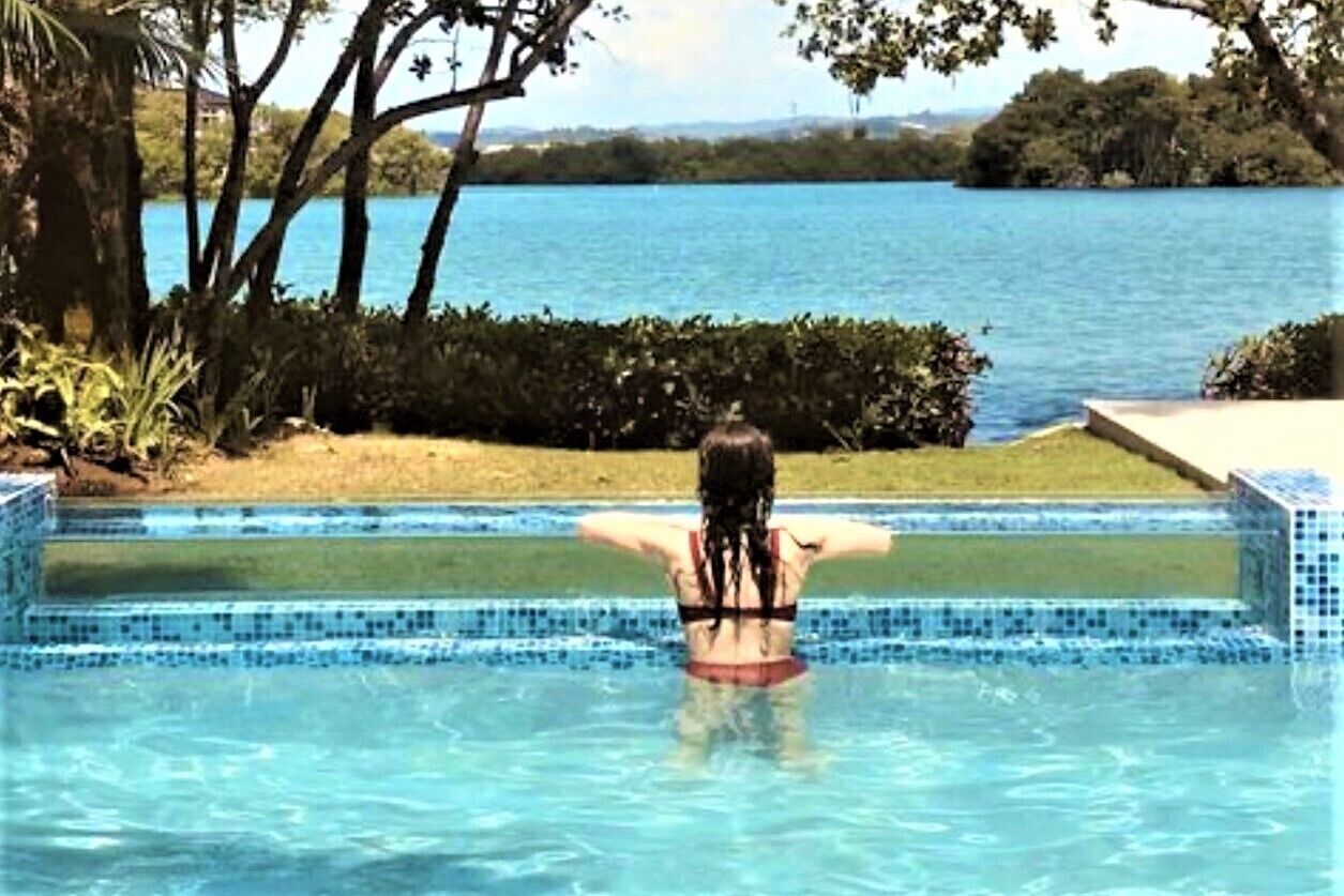 A person stands in the pool and looks at the bay.
