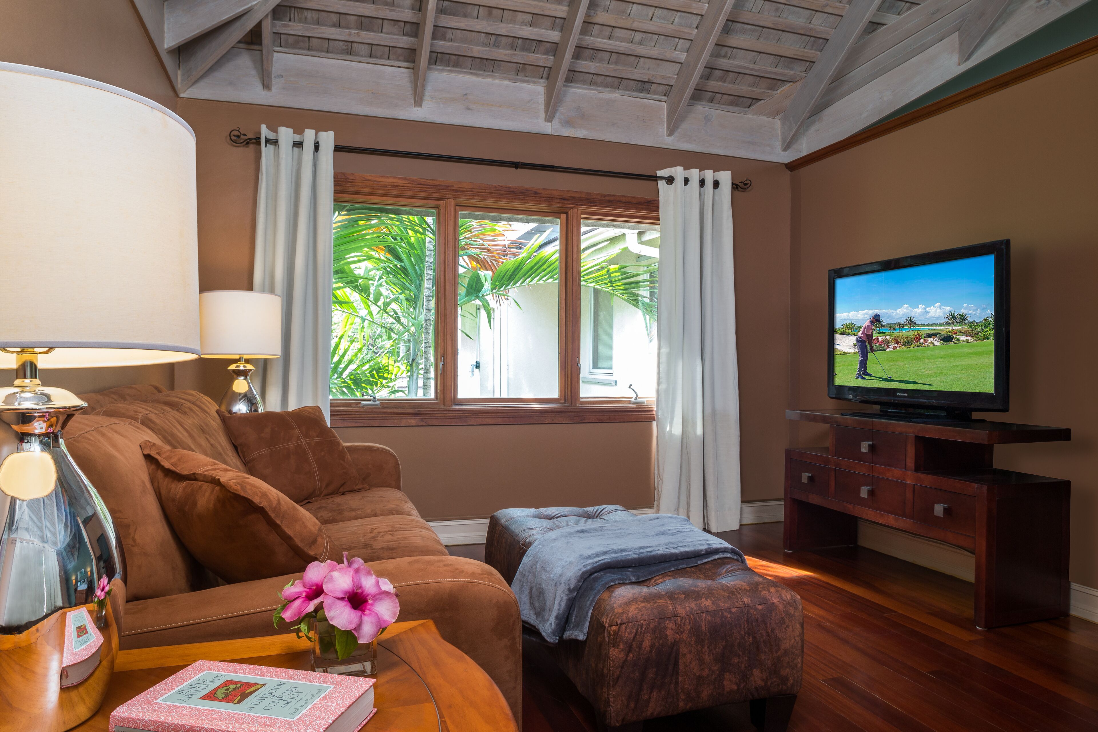 A den with a sofa, an ottoman, and a television.