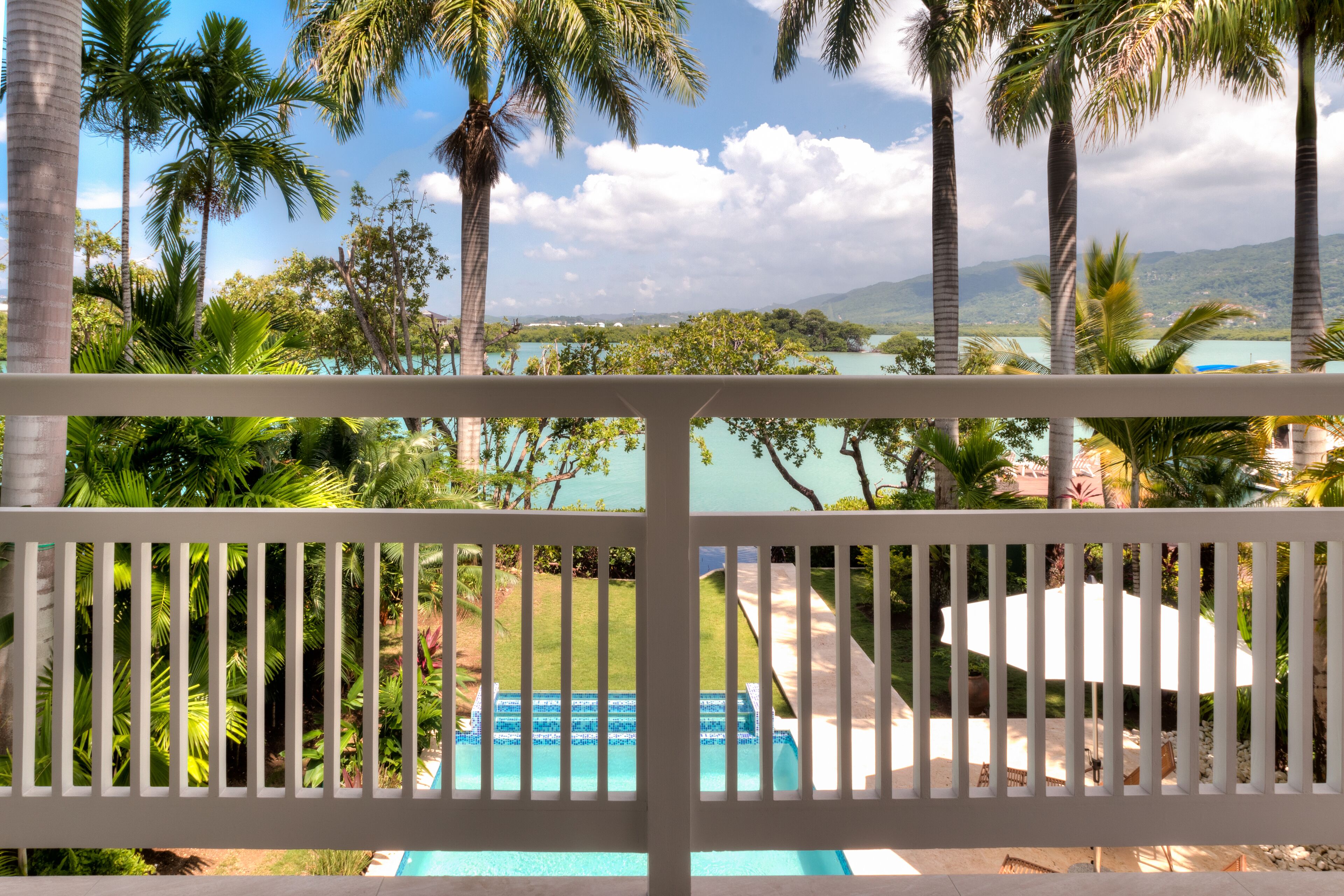 A balcony view of the pool, the palm trees, and the bay.