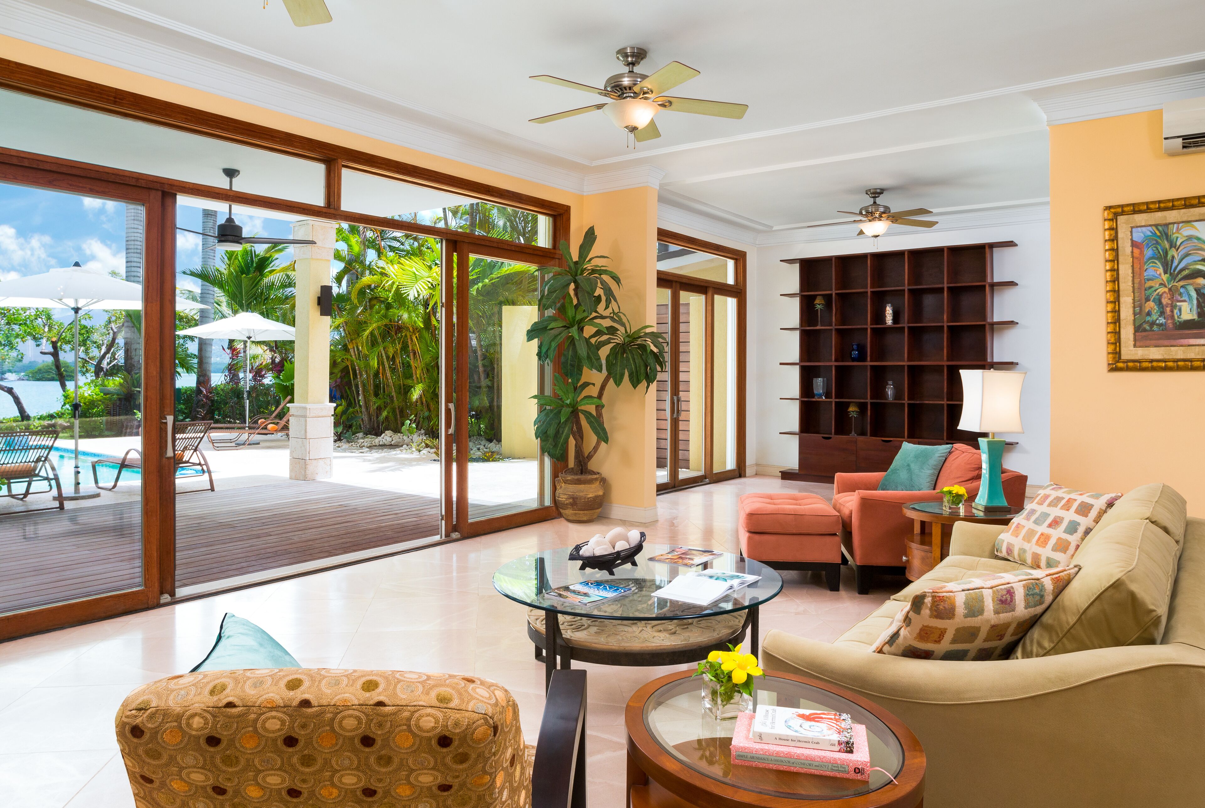 A living room with sofas and open doors to the pool deck.