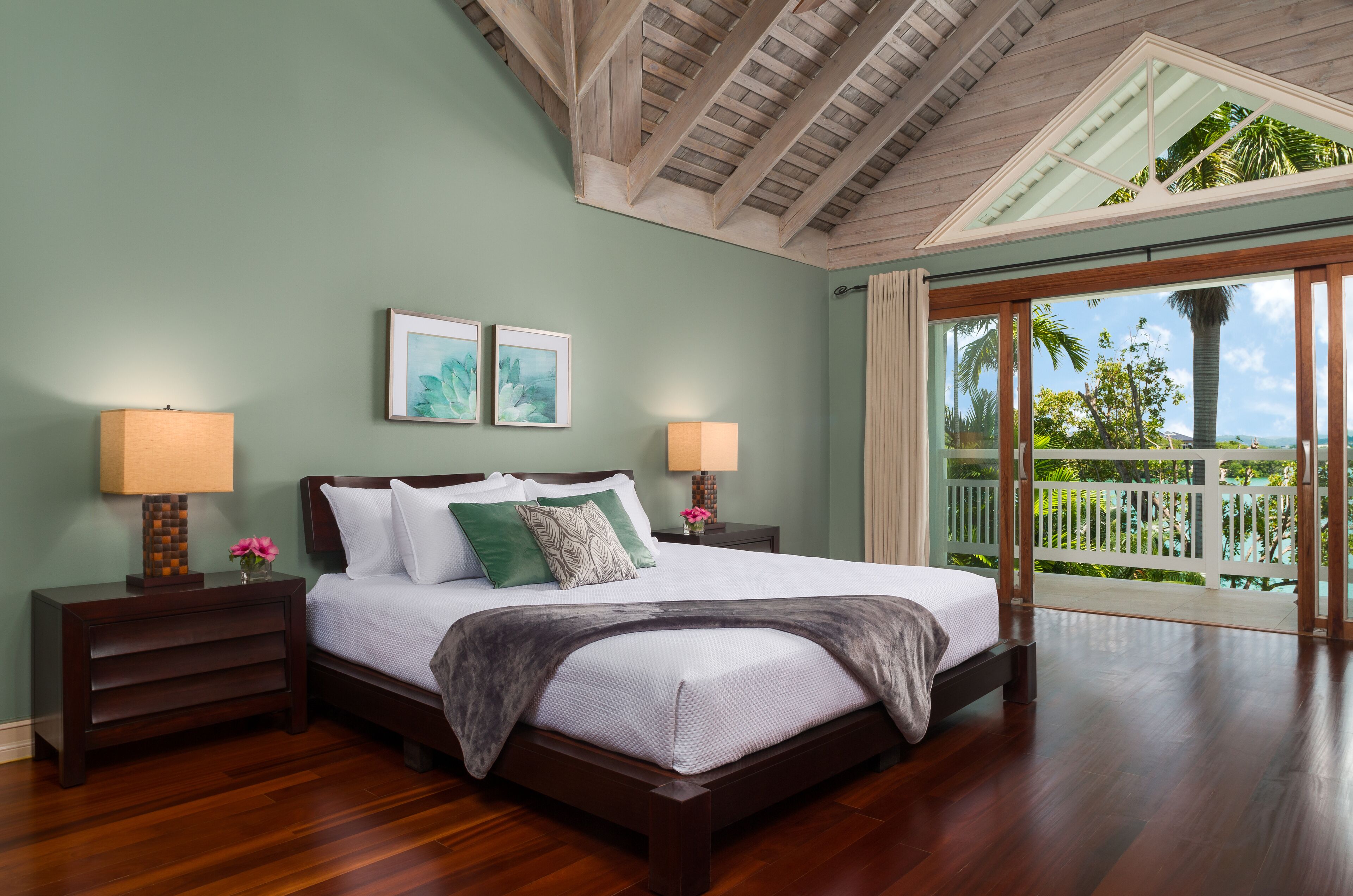 A bedroom with a double bed, green walls, and doors to a balcony.