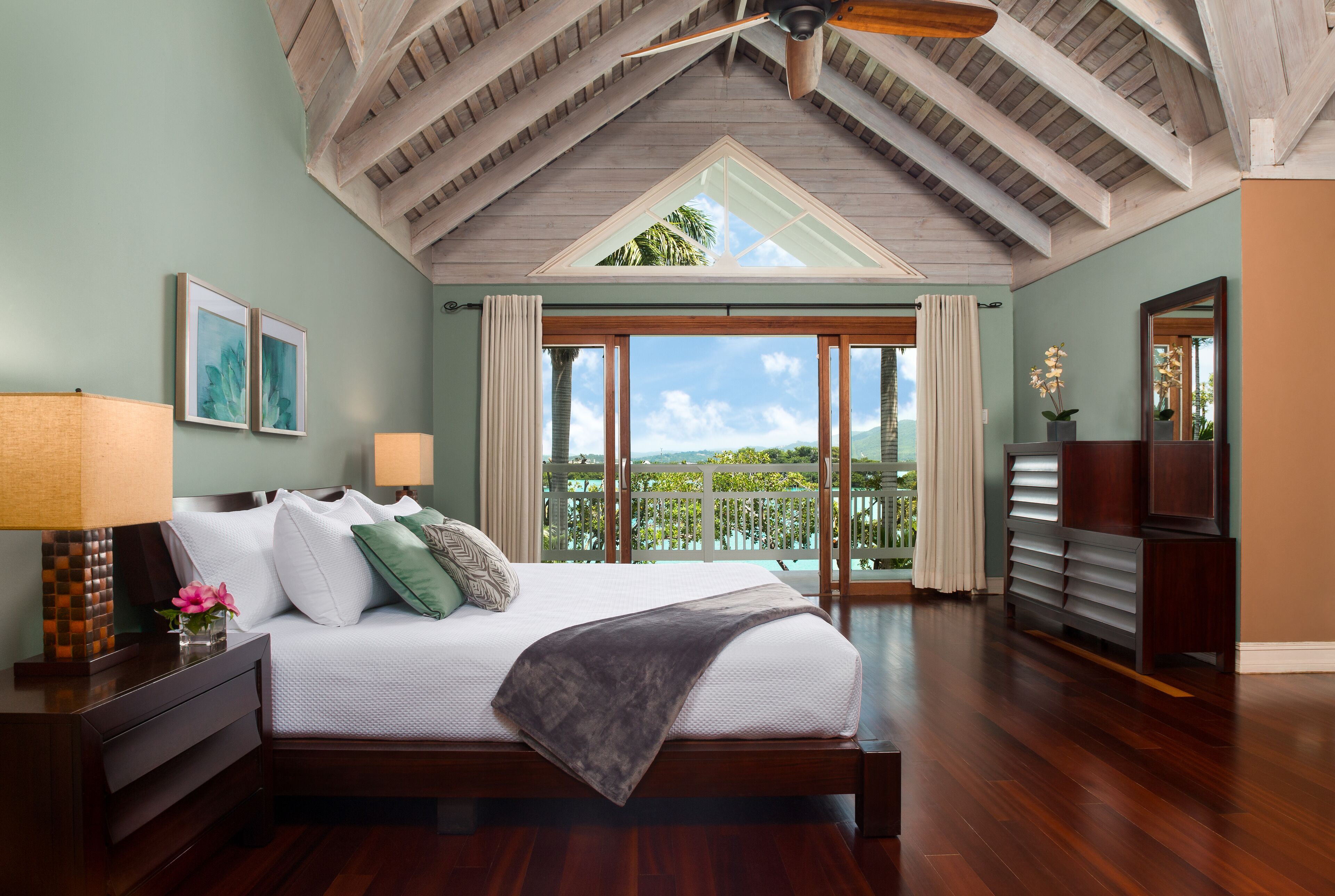 A bedroom with a double bed, a vaulted ceiling, and doors to a balcony.